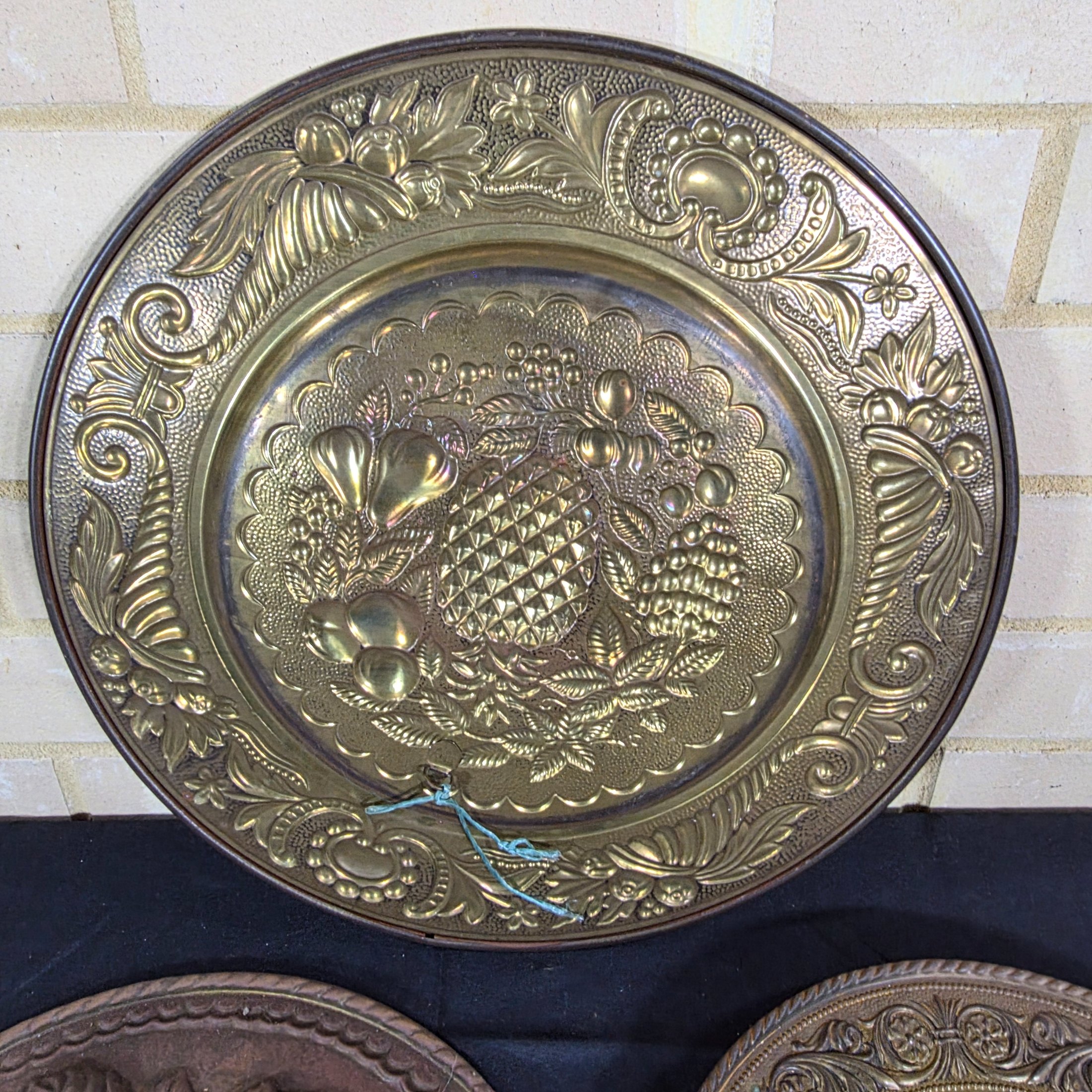A set of three vintage decorative wall plaques, featuring embossed fruit designs in brass and copper-toned metal. - View 4