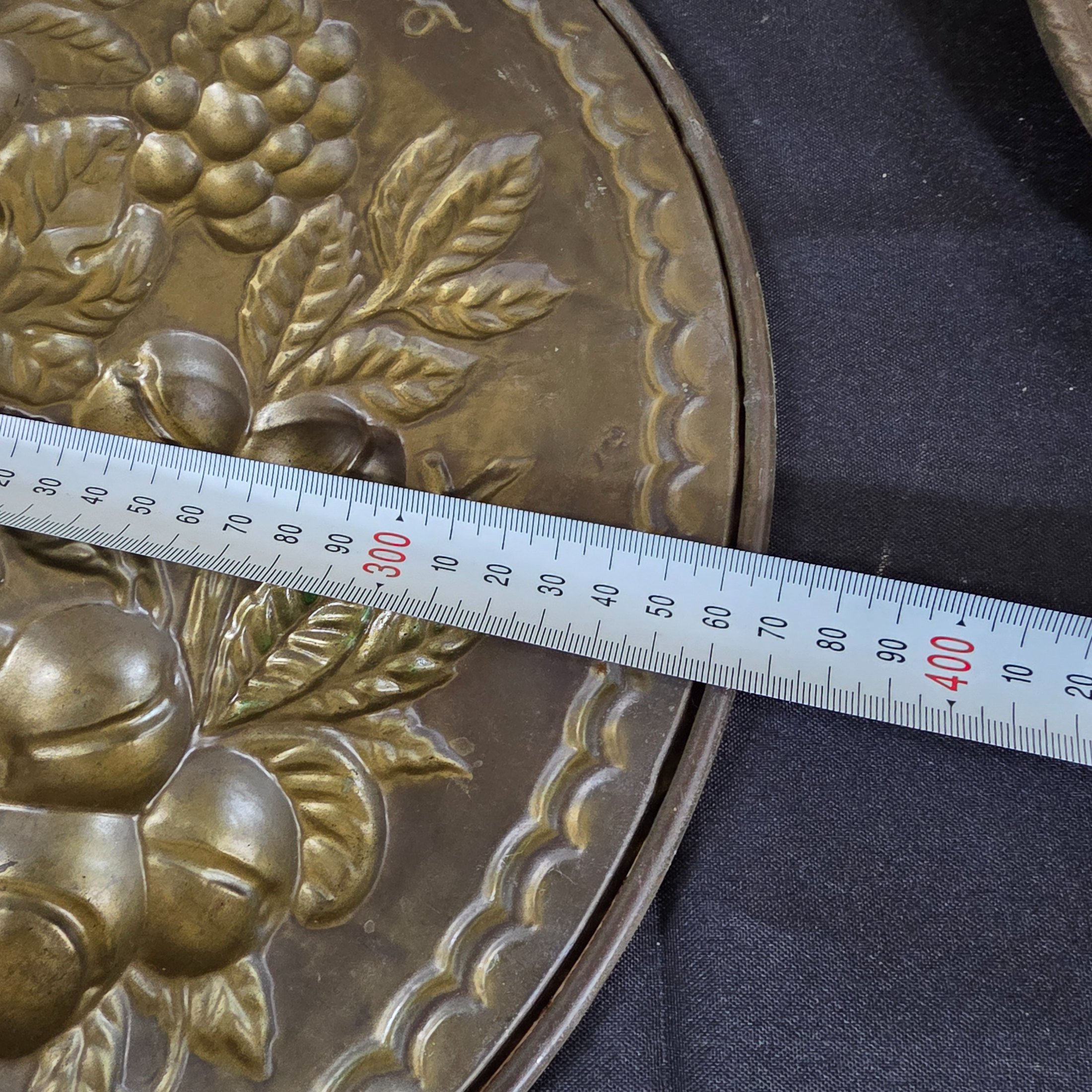 A set of three vintage decorative wall plaques, featuring embossed fruit designs in brass and copper-toned metal. - View 7