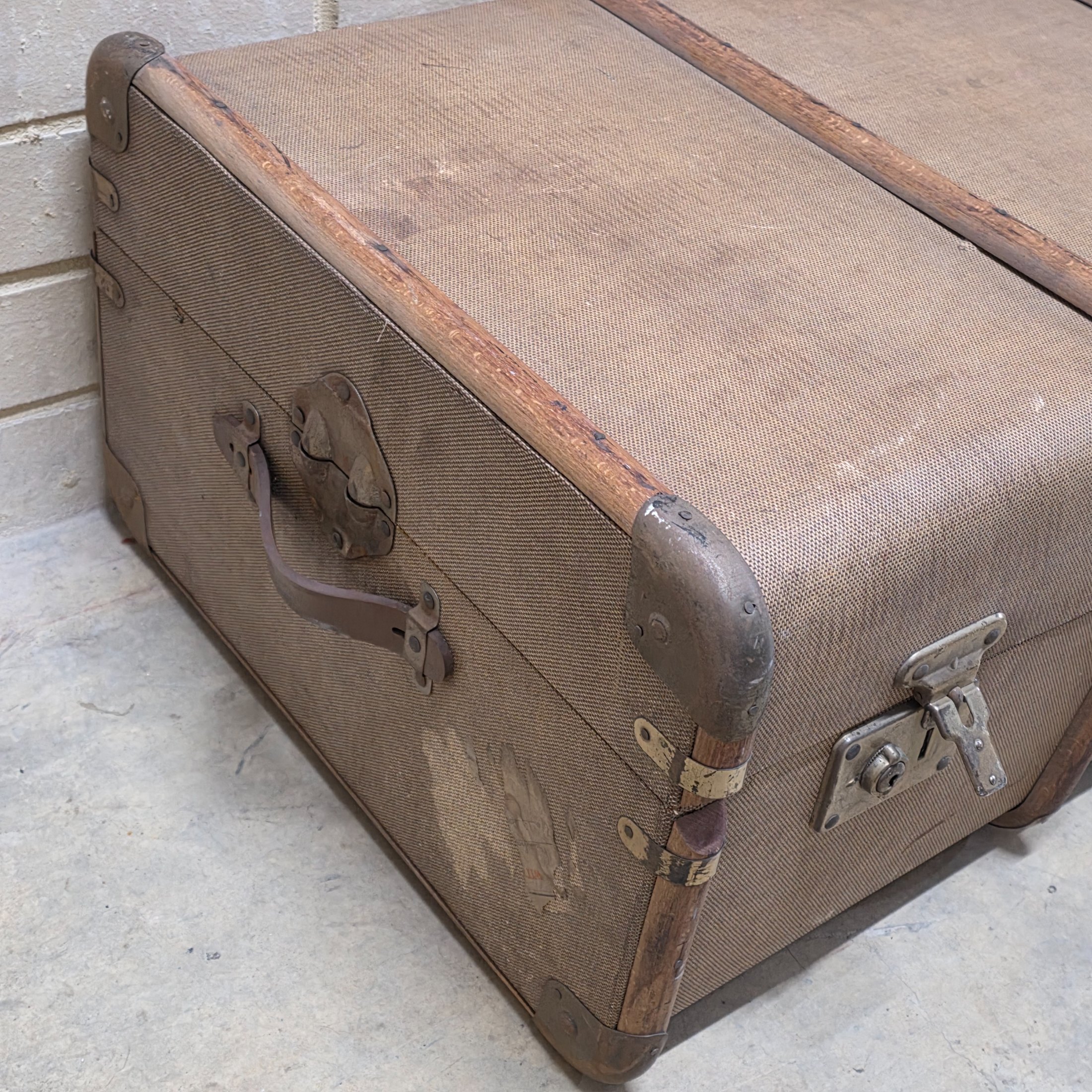 A classic vintage travel trunk from the early 20th century, made from woven fabric over a wooden frame with reinforcing wooden slats and metal hardware. - View 2