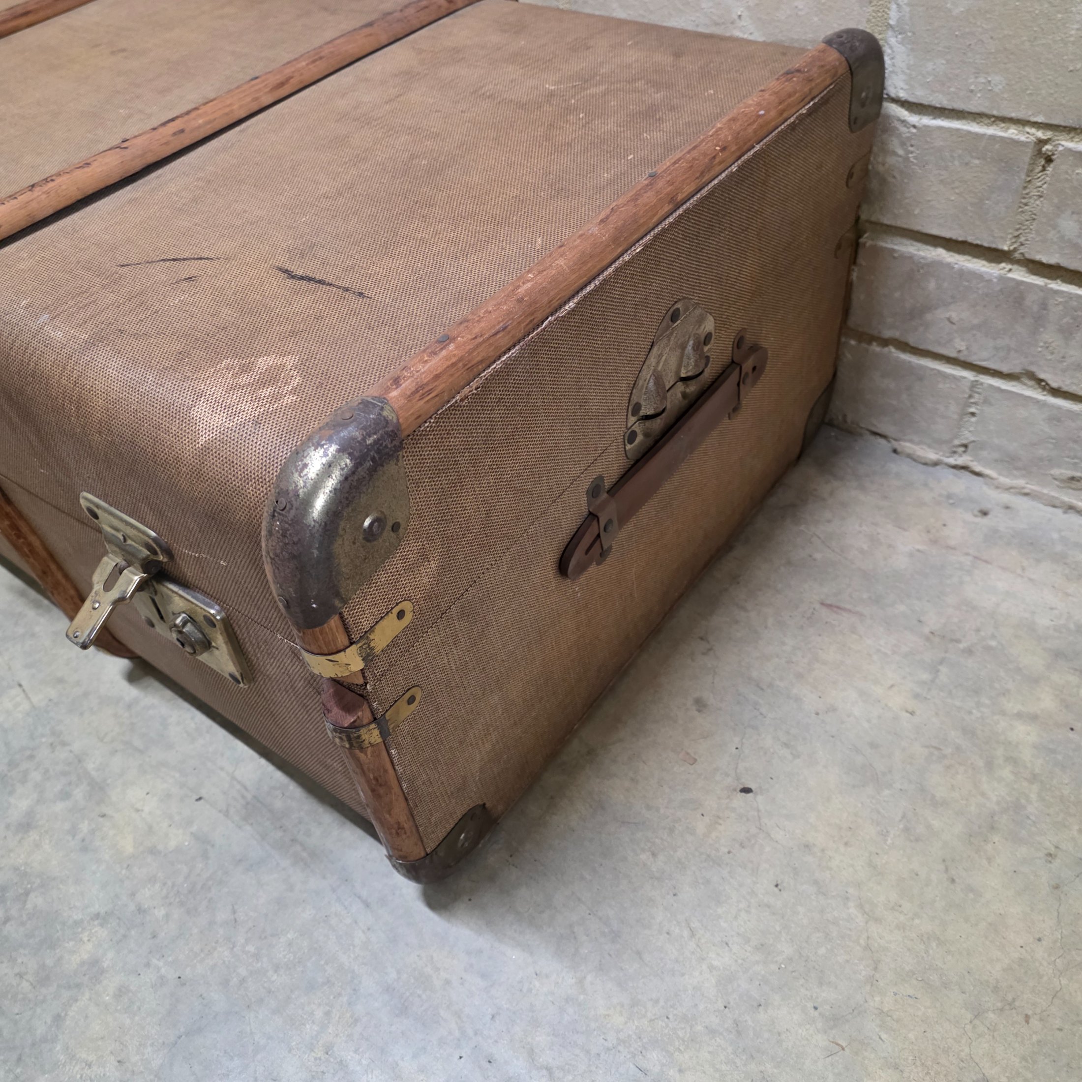 A classic vintage travel trunk from the early 20th century, made from woven fabric over a wooden frame with reinforcing wooden slats and metal hardware. - View 3