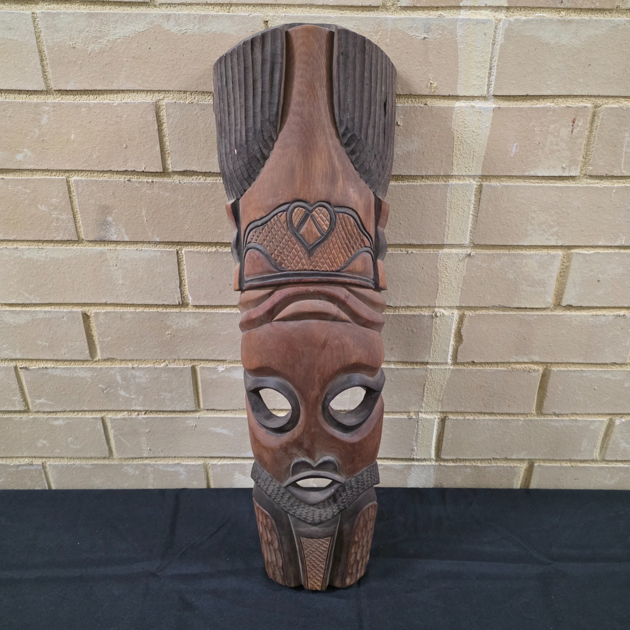 A striking vintage hand-carved wooden mask, featuring intricate tribal-style detailing and a rich dark wood finish, likely from the mid-20th century.