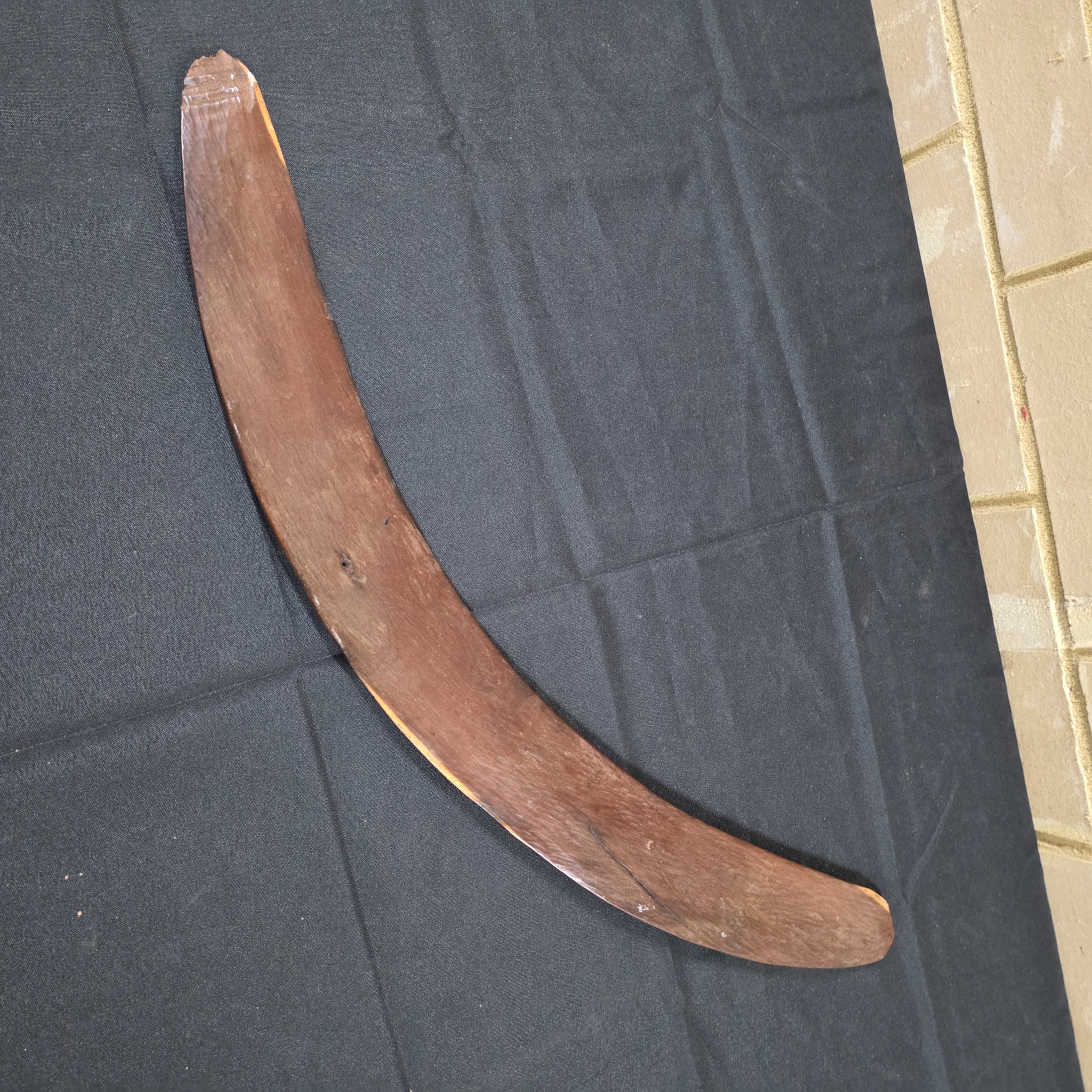 A vintage hand-carved wooden boomerang with a natural dark brown finish, approximately 62cm in length. - View 2