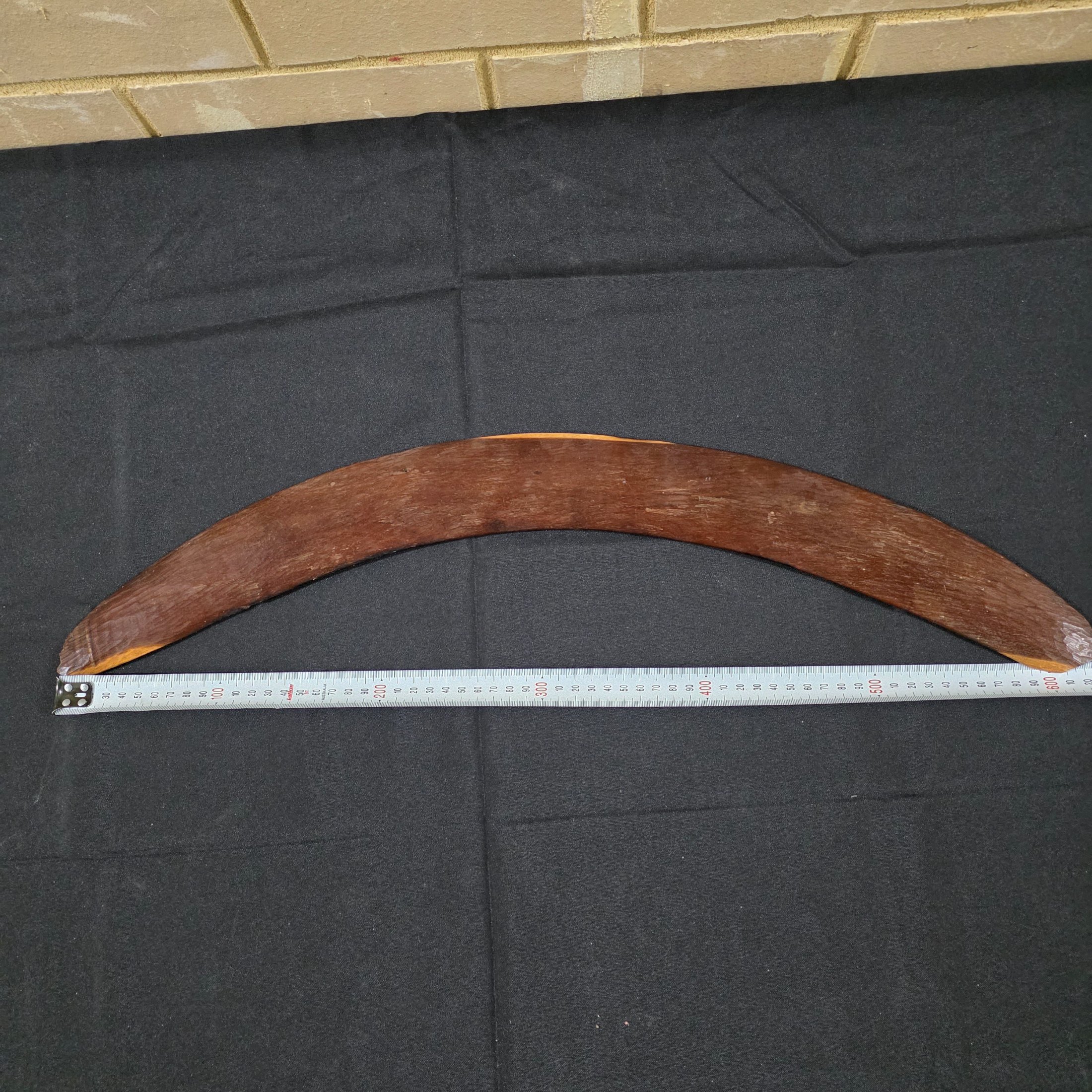 A vintage hand-carved wooden boomerang with a natural dark brown finish, approximately 62cm in length. - View 6