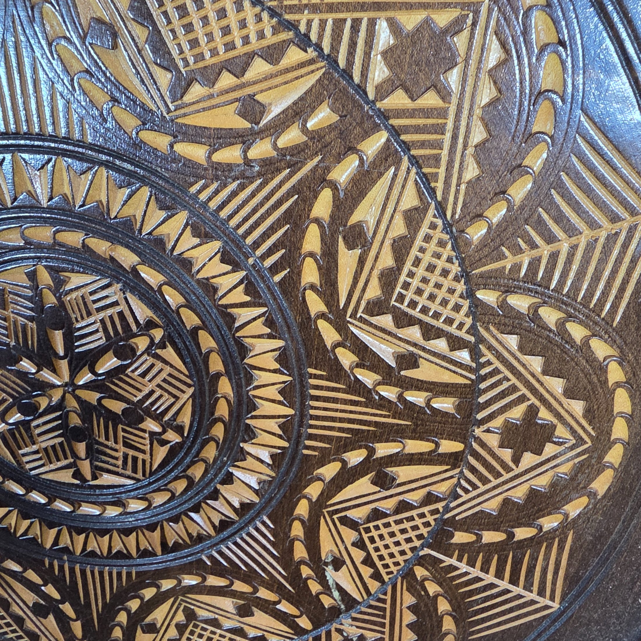 A vintage hand-carved wooden decorative plate, featuring intricate geometric and radial chip-carved patterns revealing lighter wood beneath a dark stain, likely mid-20th century. - View 2
