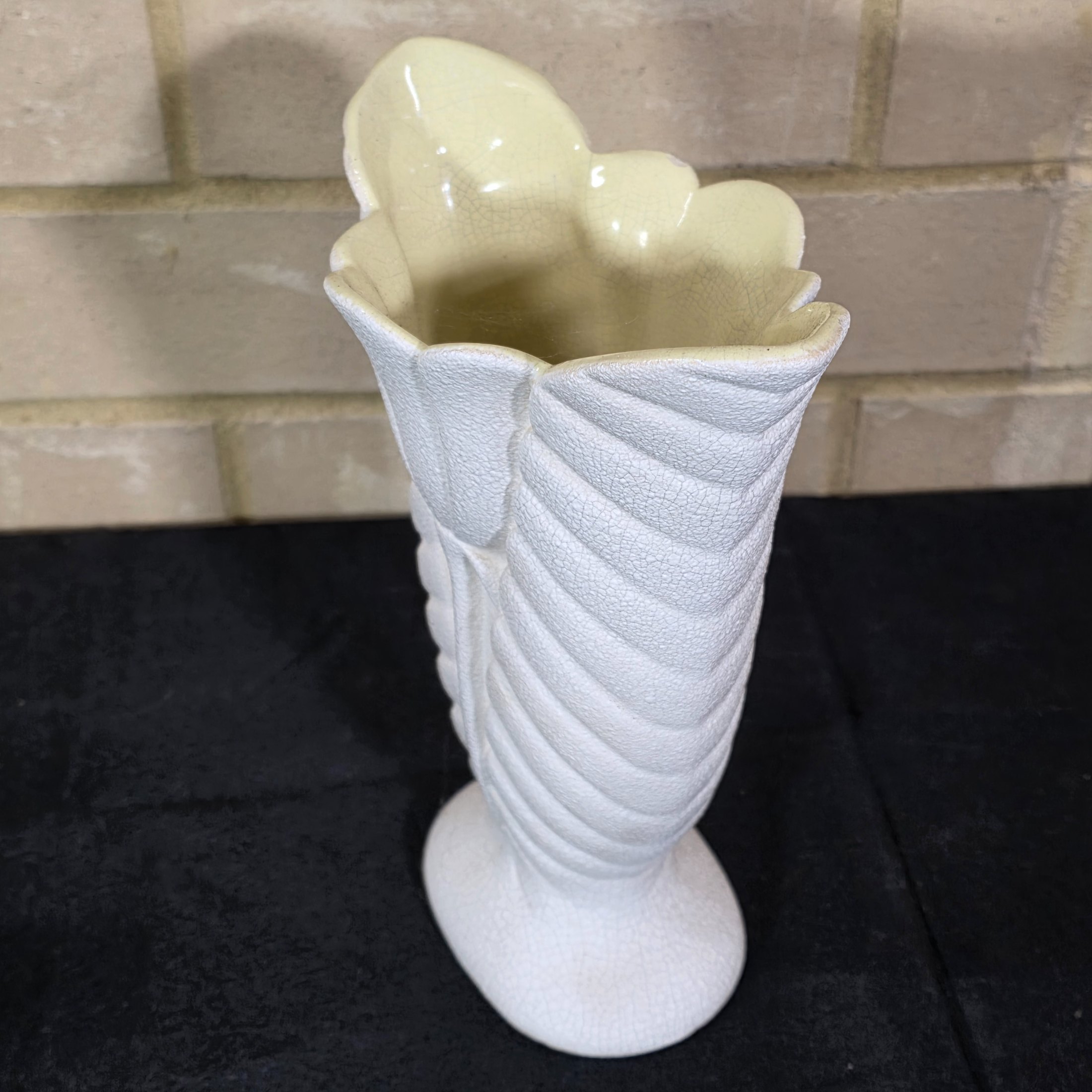 A striking white ceramic vase, likely from the mid-20th century, distinguished by its textured, fluted body reminiscent of a shell or stylized leaf. The piece features a prominent crackle glaze on both its off-white exterior and pale yellow interior. - View 2