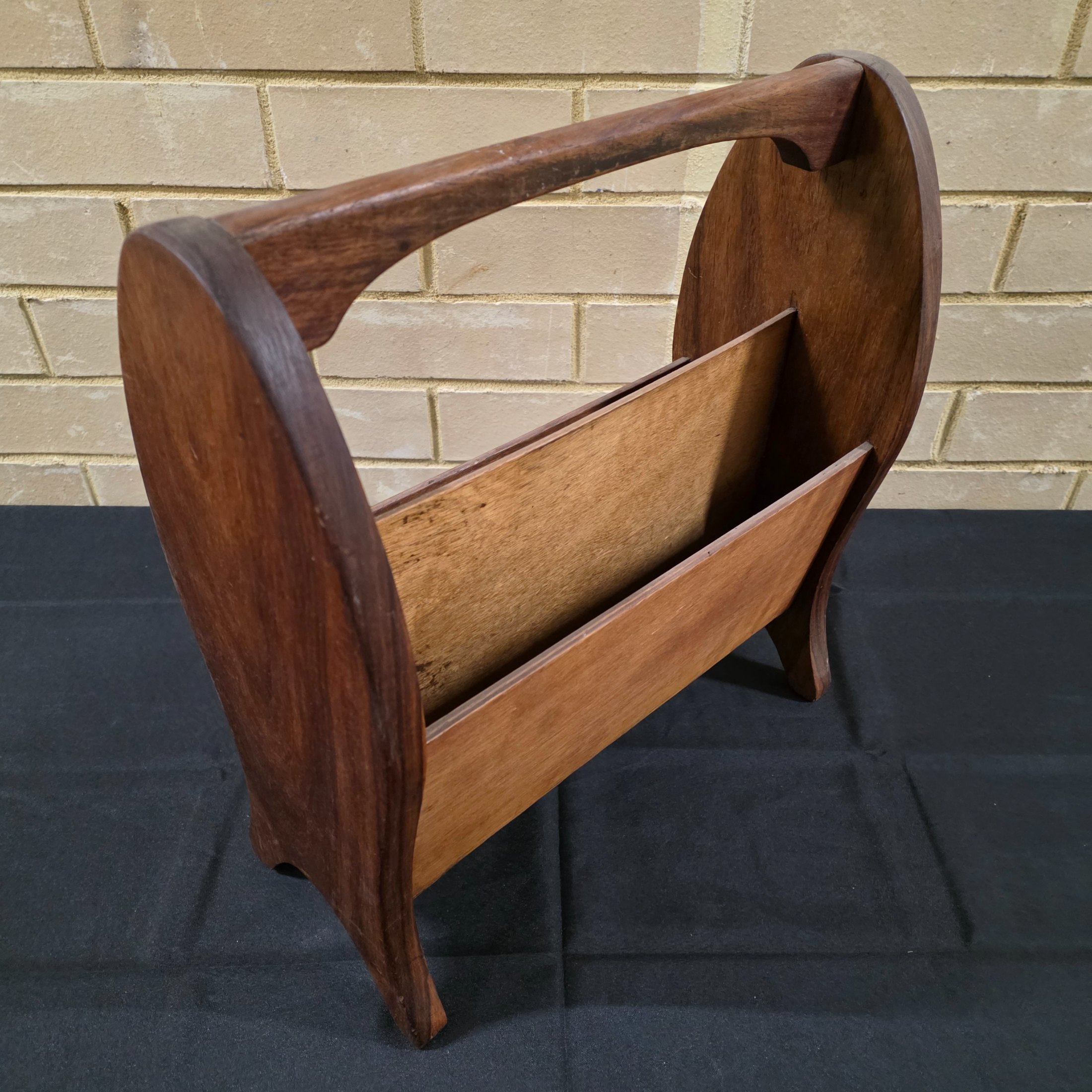 A classic vintage mid-century wooden magazine rack, featuring a curved handle and two functional compartments for storage. This piece showcases the simple, elegant design characteristic of its era, crafted from solid wood with a warm, natural finish. - View 3