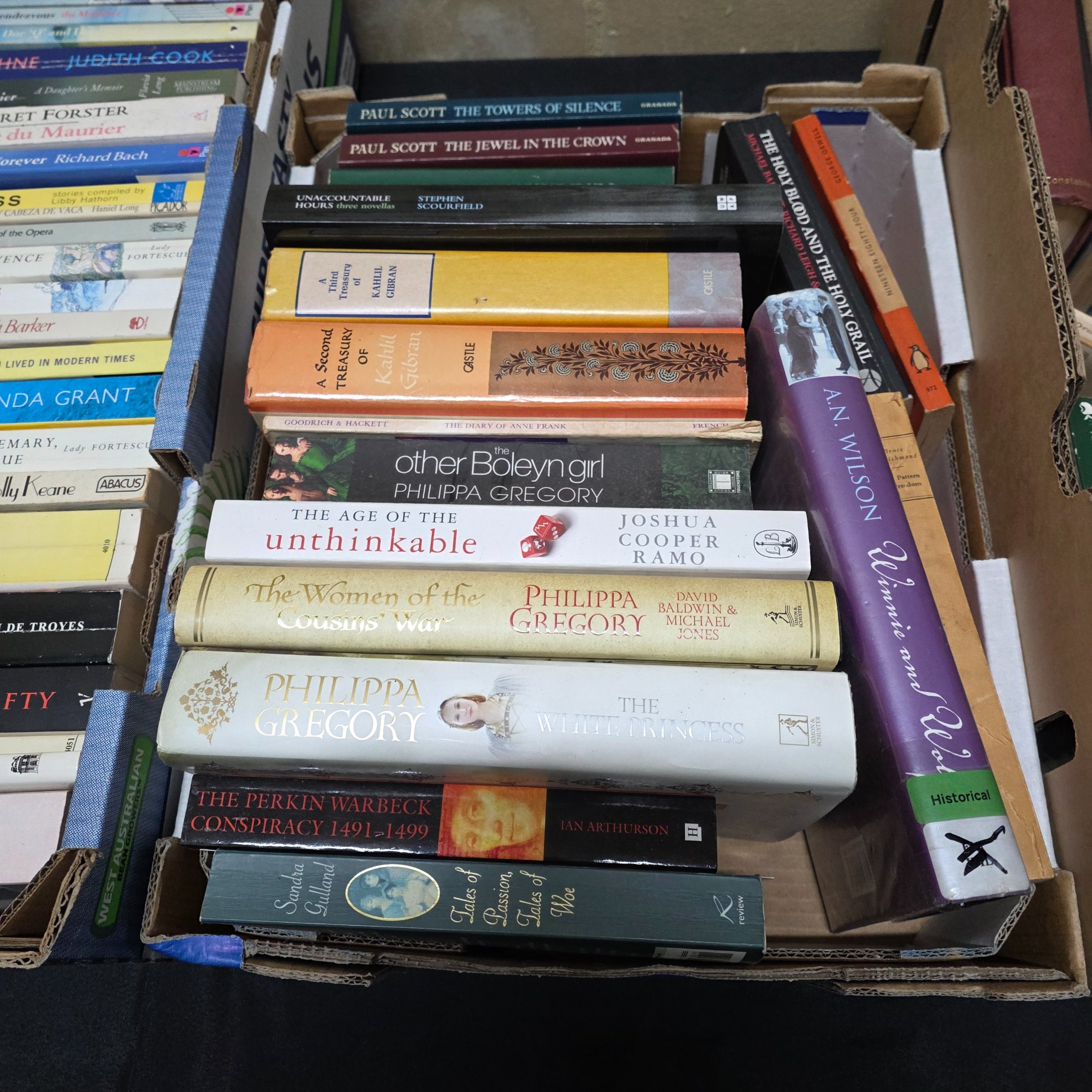 A large collection of assorted paperback and hardcover books, stacked in multiple cardboard boxes. - View 4