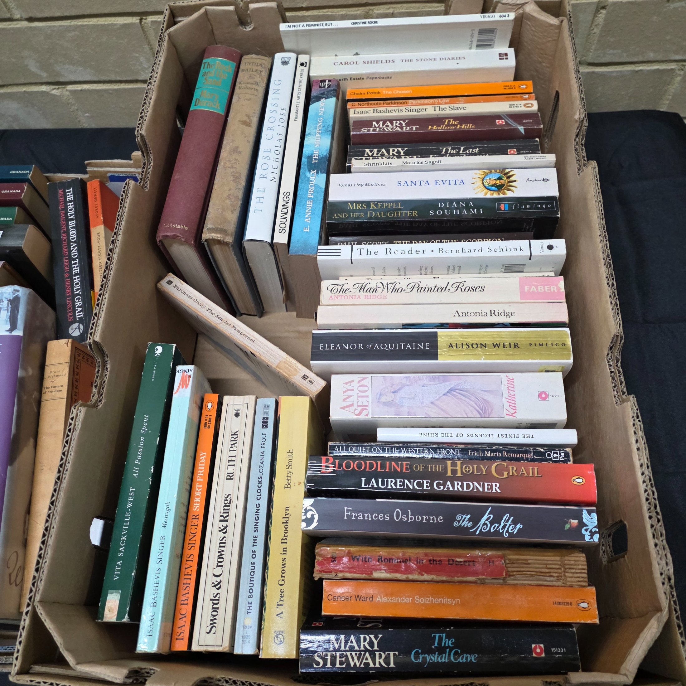 A large collection of assorted paperback and hardcover books, stacked in multiple cardboard boxes. - View 5