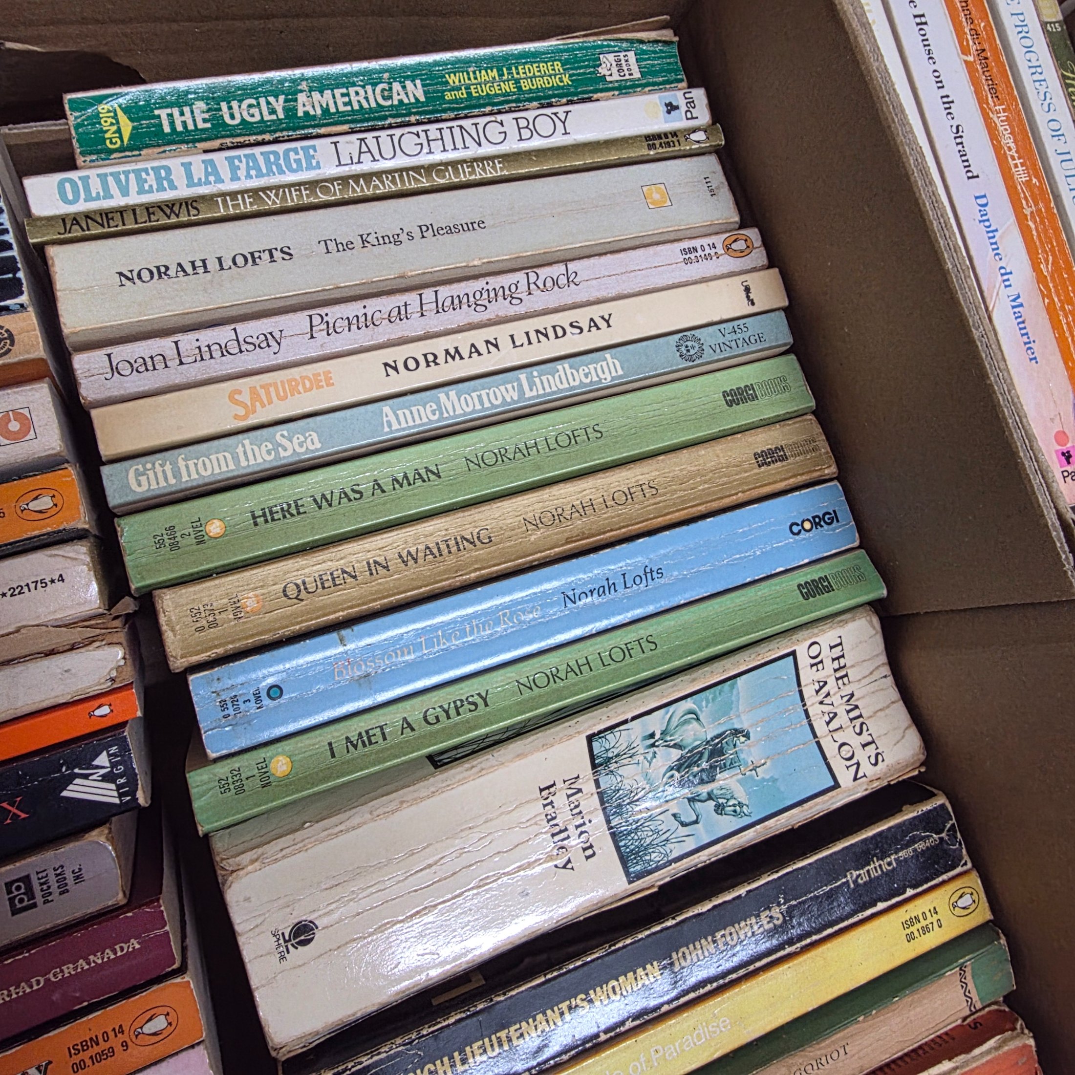 A large collection of assorted paperback and hardcover books, stacked in multiple cardboard boxes. - View 7