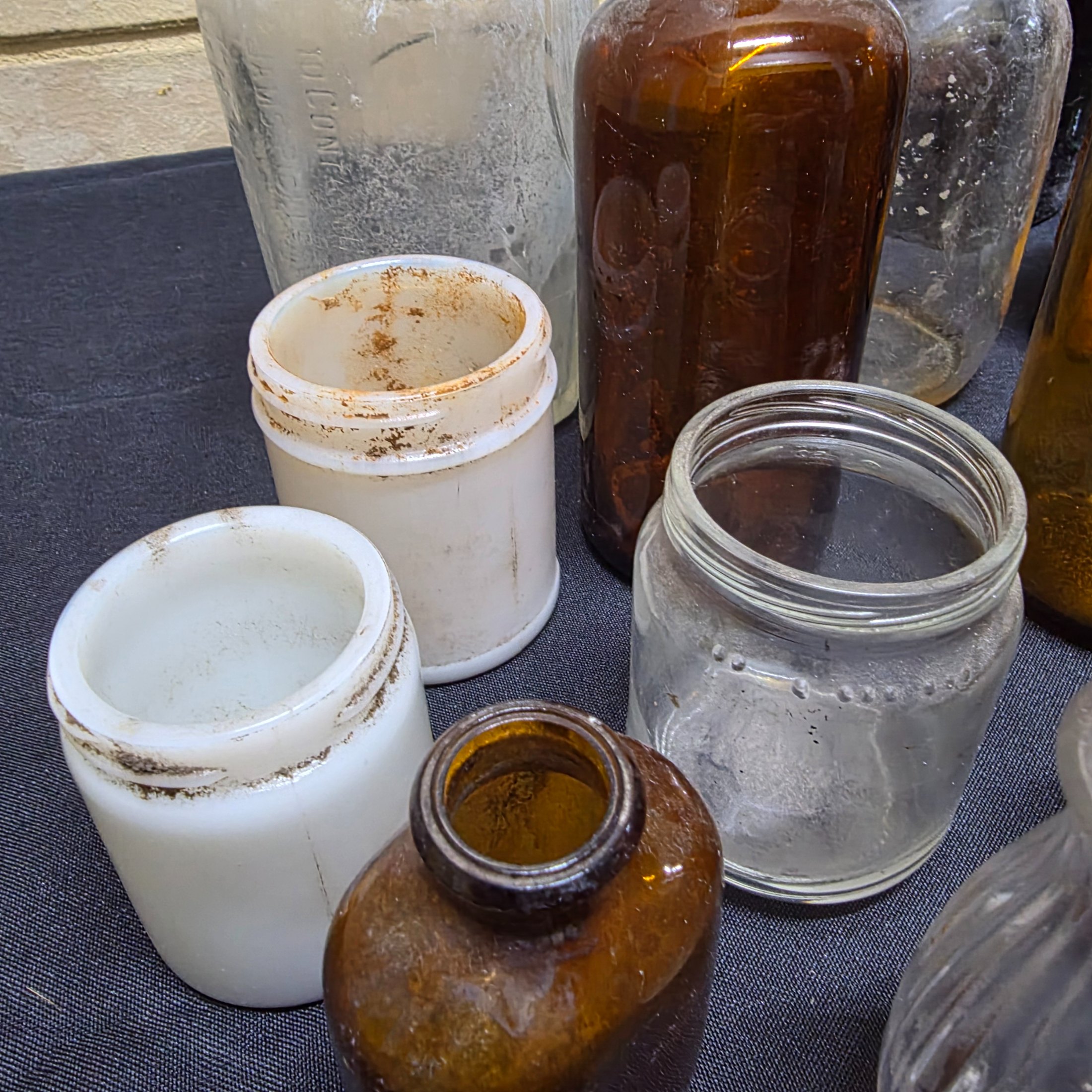 A diverse collection of antique and vintage glass and ceramic bottles and jars, dating from the late 19th to mid-20th century, showcasing various styles and materials. - View 7