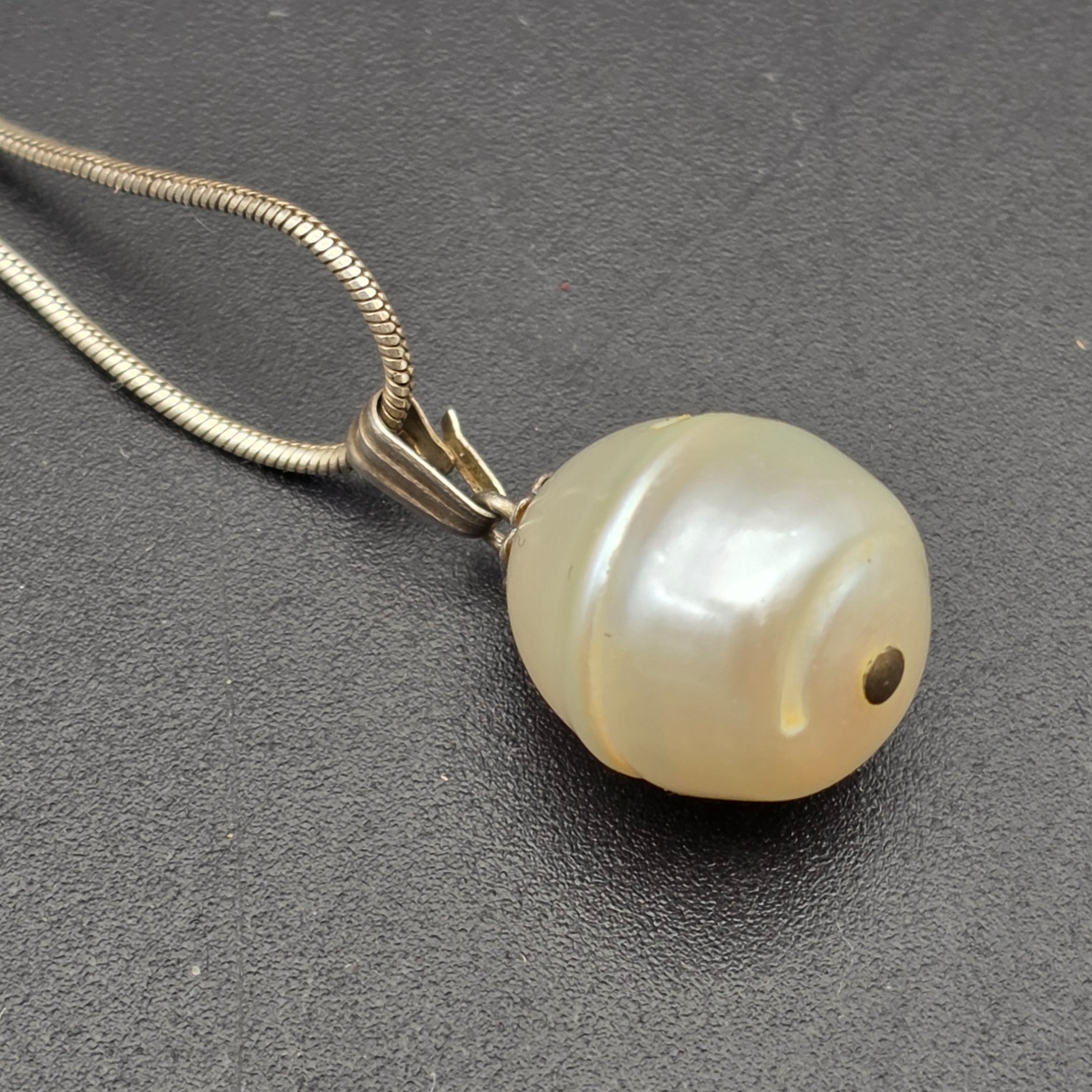 A matching Paul Kennedy sterling silver and baroque freshwater pearl necklace and earring set. This contemporary jewellery suite features a snake chain necklace with a single irregular pearl pendant and a pair of coordinating hook earrings, each set with a baroque pearl. - View 4