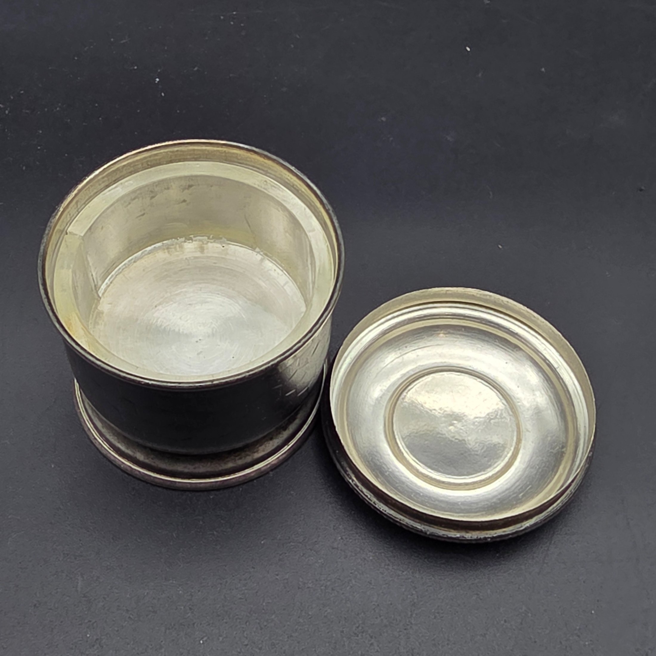 A collection of four vintage silver-toned items, including a sterling silver napkin ring, a second napkin ring, a ribbed cup, and a lidded box, dating from the early to mid-20th century. - View 8