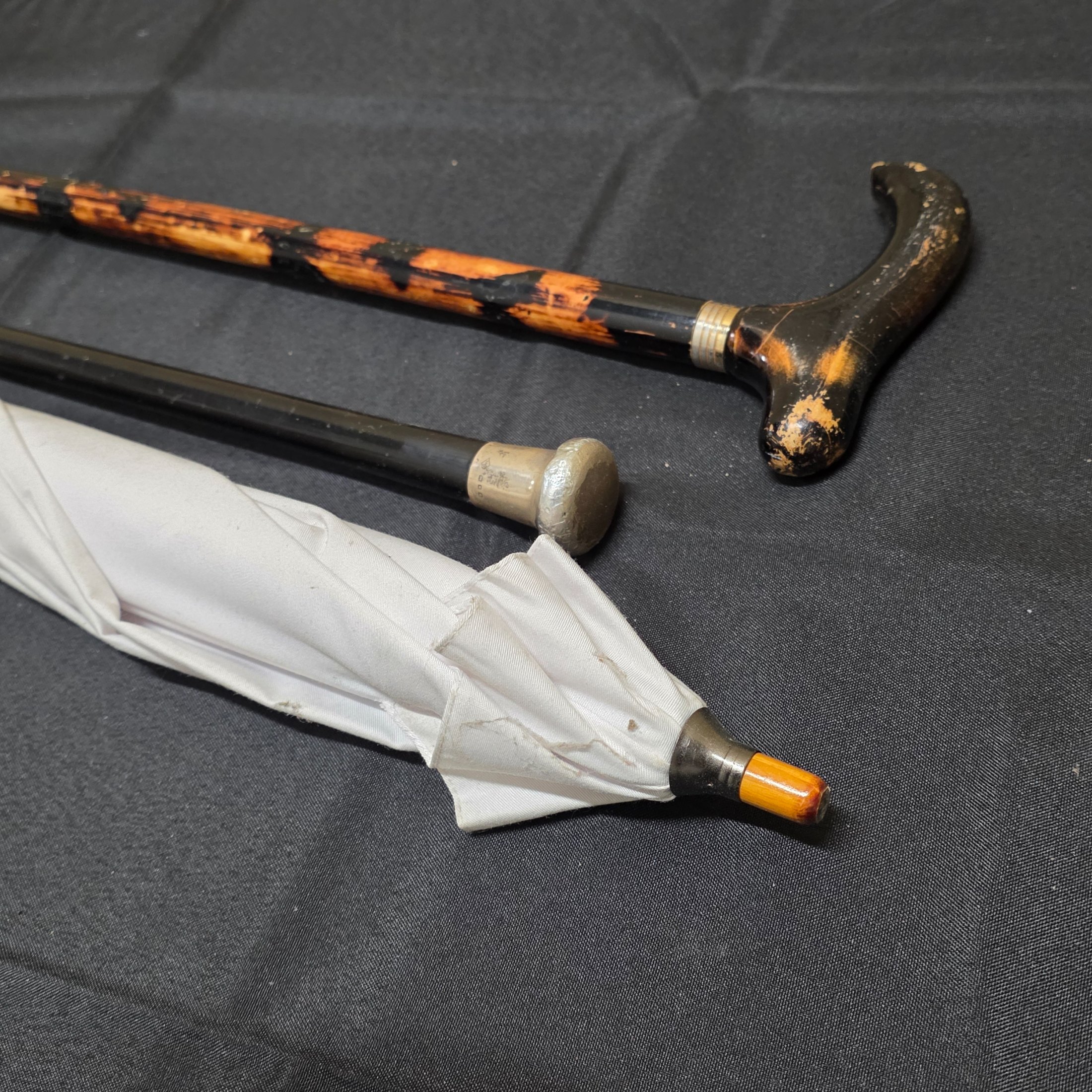 A collection of two vintage walking sticks and a white Sunbella umbrella, including one walking stick with a hallmarked sterling silver cap.