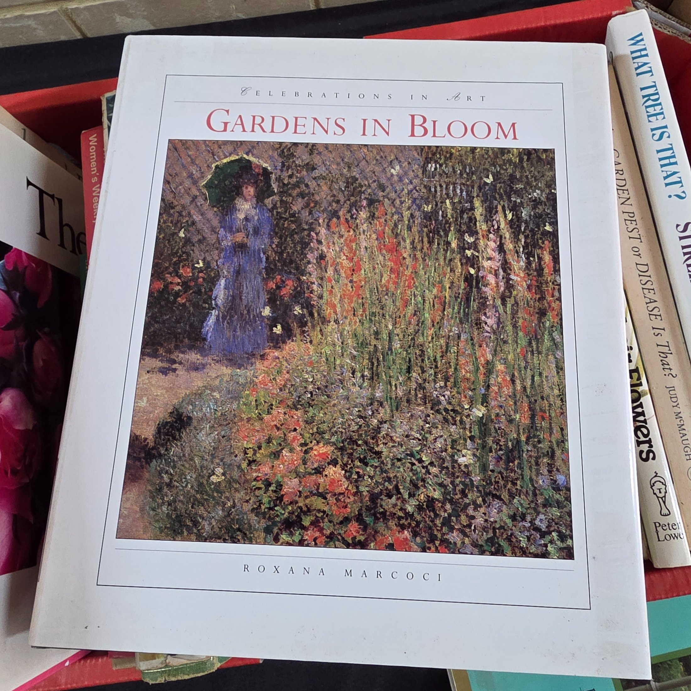A box containing approximately 20-25 assorted gardening books, including titles on flowers, plant identification, and general horticultural practices. - View 4