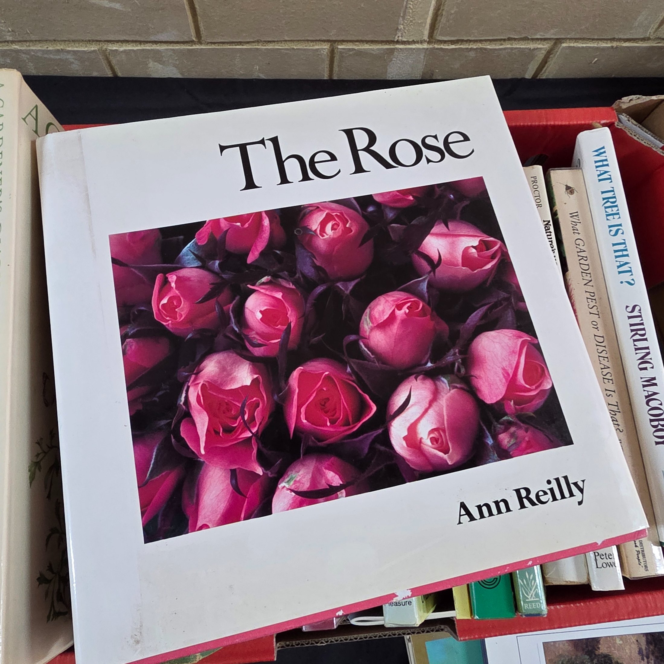 A box containing approximately 20-25 assorted gardening books, including titles on flowers, plant identification, and general horticultural practices. - View 5