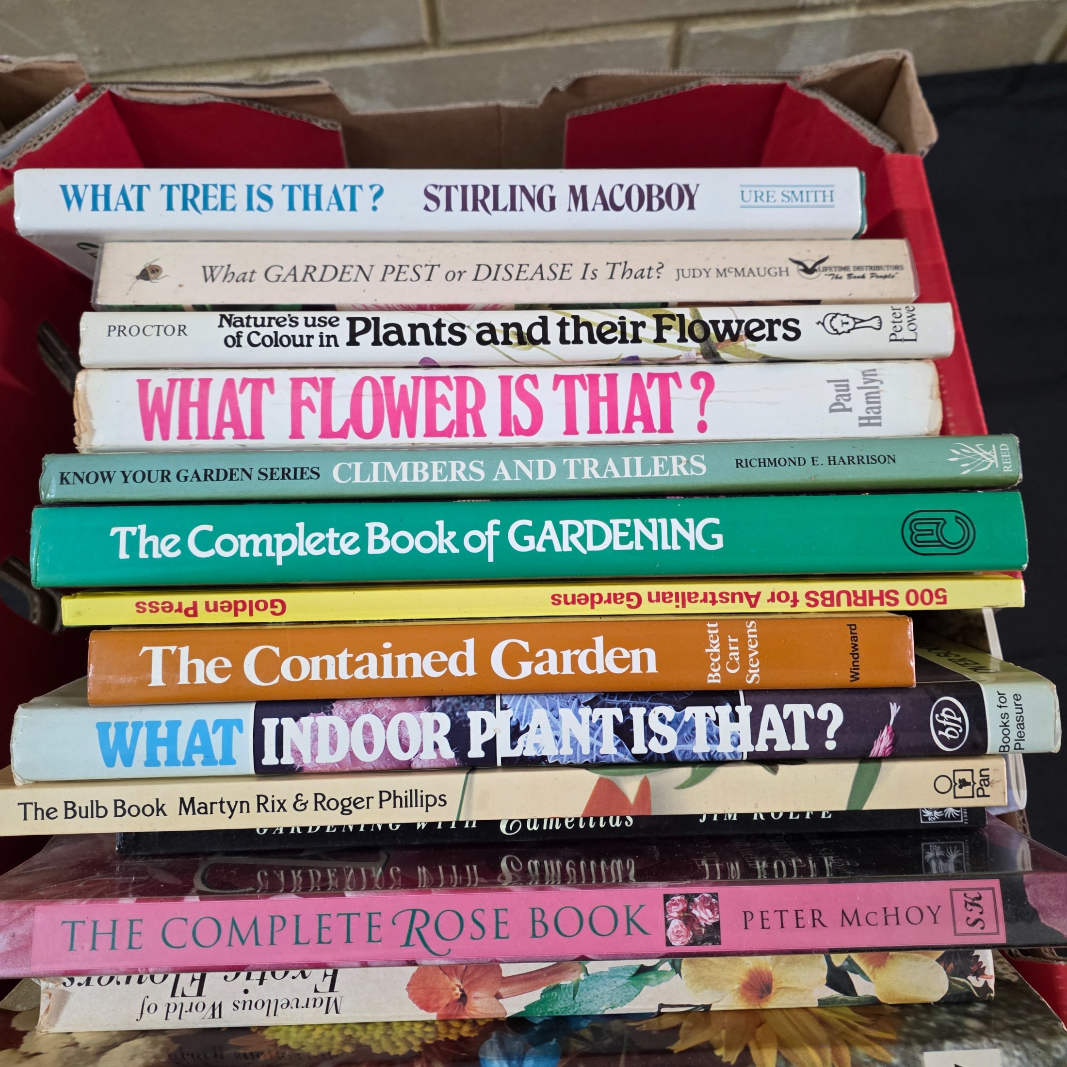 A box containing approximately 20-25 assorted gardening books, including titles on flowers, plant identification, and general horticultural practices. - View 7
