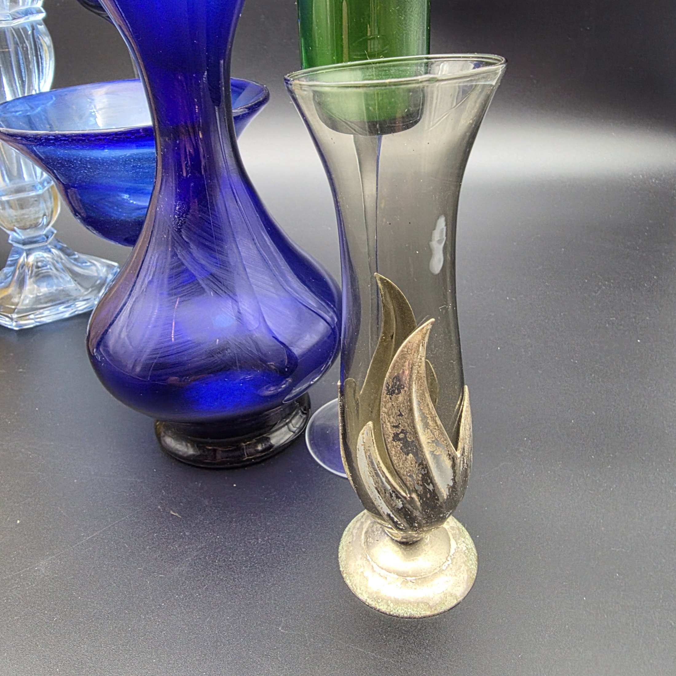 A varied collection of ten vintage coloured glass pieces, including vases, bowls, and stemmed glasses, showcasing different styles and manufacturing techniques from the mid-20th century. The array features shades of cobalt blue, amber, yellow, green, and smoky grey, offering a diverse decorative grouping. - View 2
