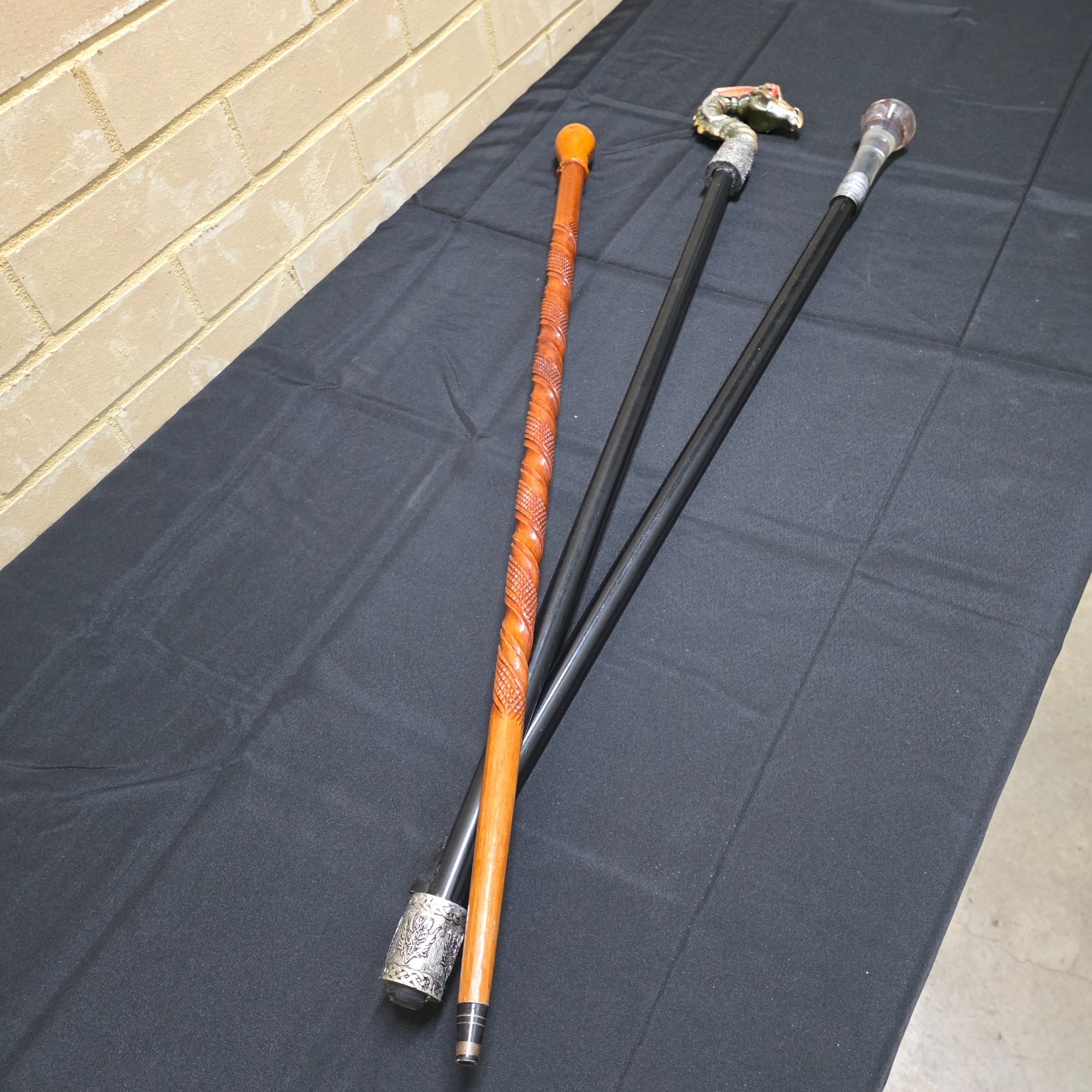 A collection of three vintage decorative walking sticks, featuring a carved wooden handle, a dragon-head handle, and a clear resin handle with an embedded scorpion. - View 2