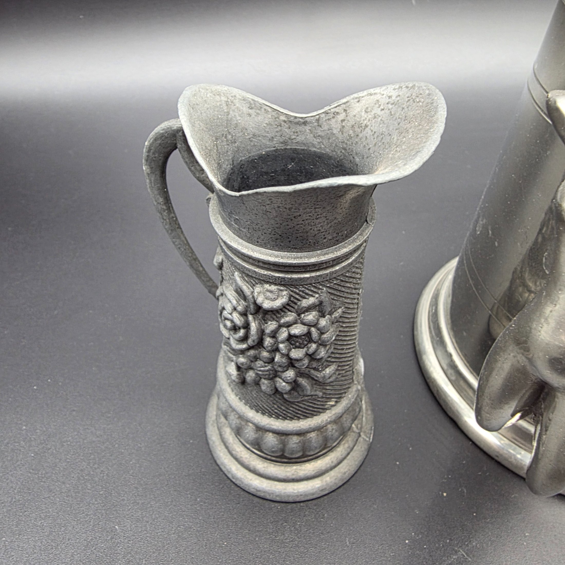 A collection of three traditional English pewter vessels, including a tankard with a unique nude figure handle, and two pitchers. These pieces originate from Sheffield, a city historically renowned for its metalwork and pewter manufacturing. - View 3