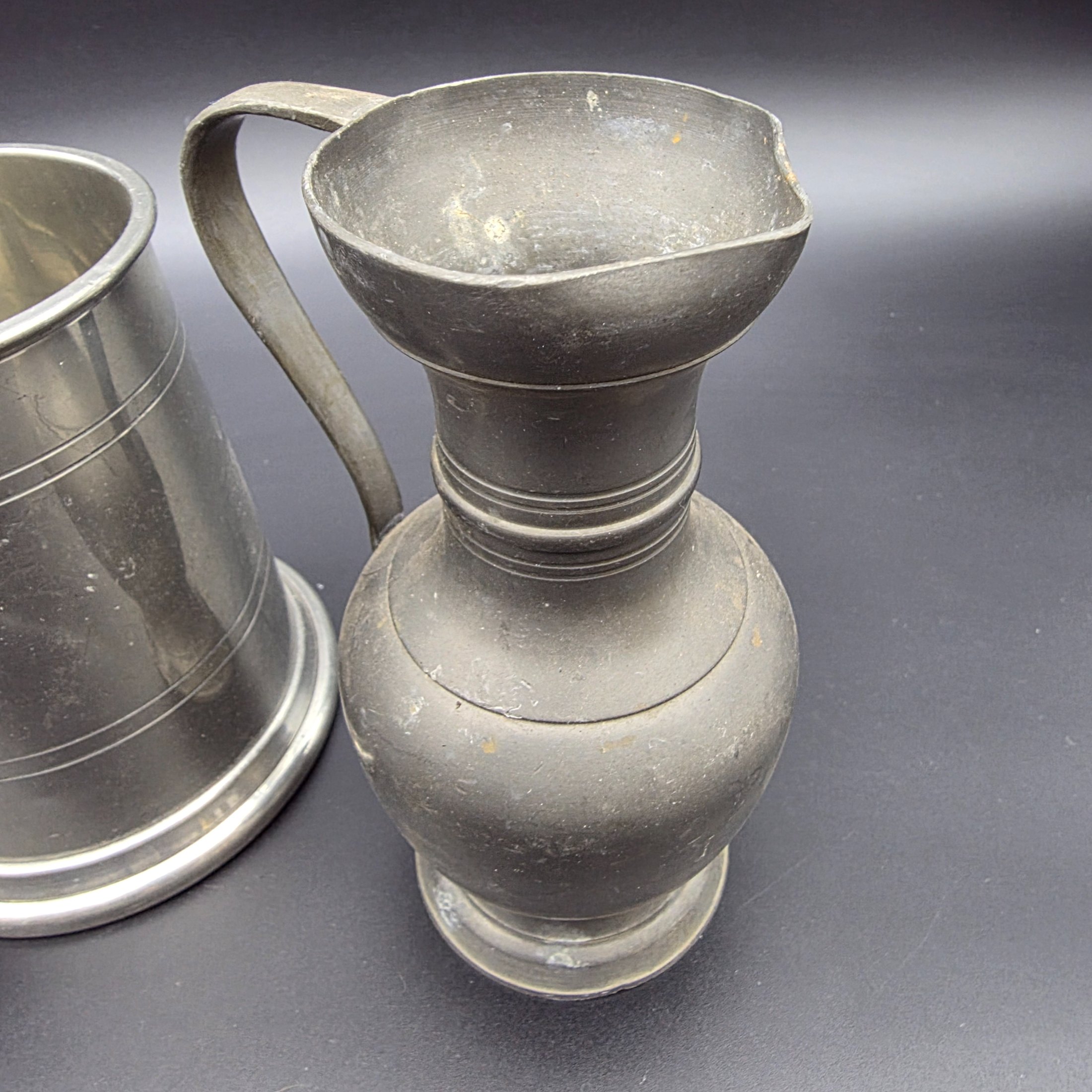A collection of three traditional English pewter vessels, including a tankard with a unique nude figure handle, and two pitchers. These pieces originate from Sheffield, a city historically renowned for its metalwork and pewter manufacturing. - View 4