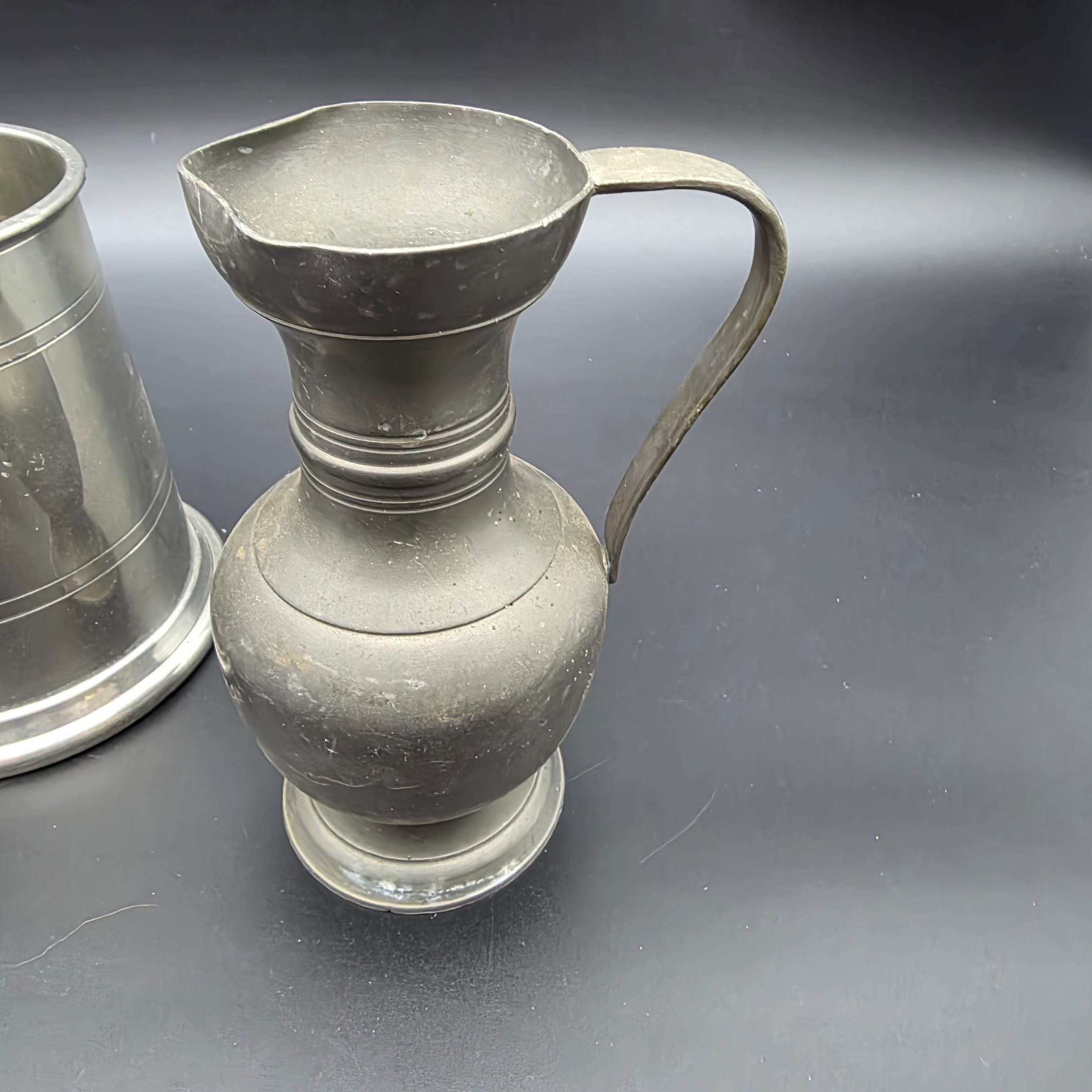 A collection of three traditional English pewter vessels, including a tankard with a unique nude figure handle, and two pitchers. These pieces originate from Sheffield, a city historically renowned for its metalwork and pewter manufacturing. - View 5