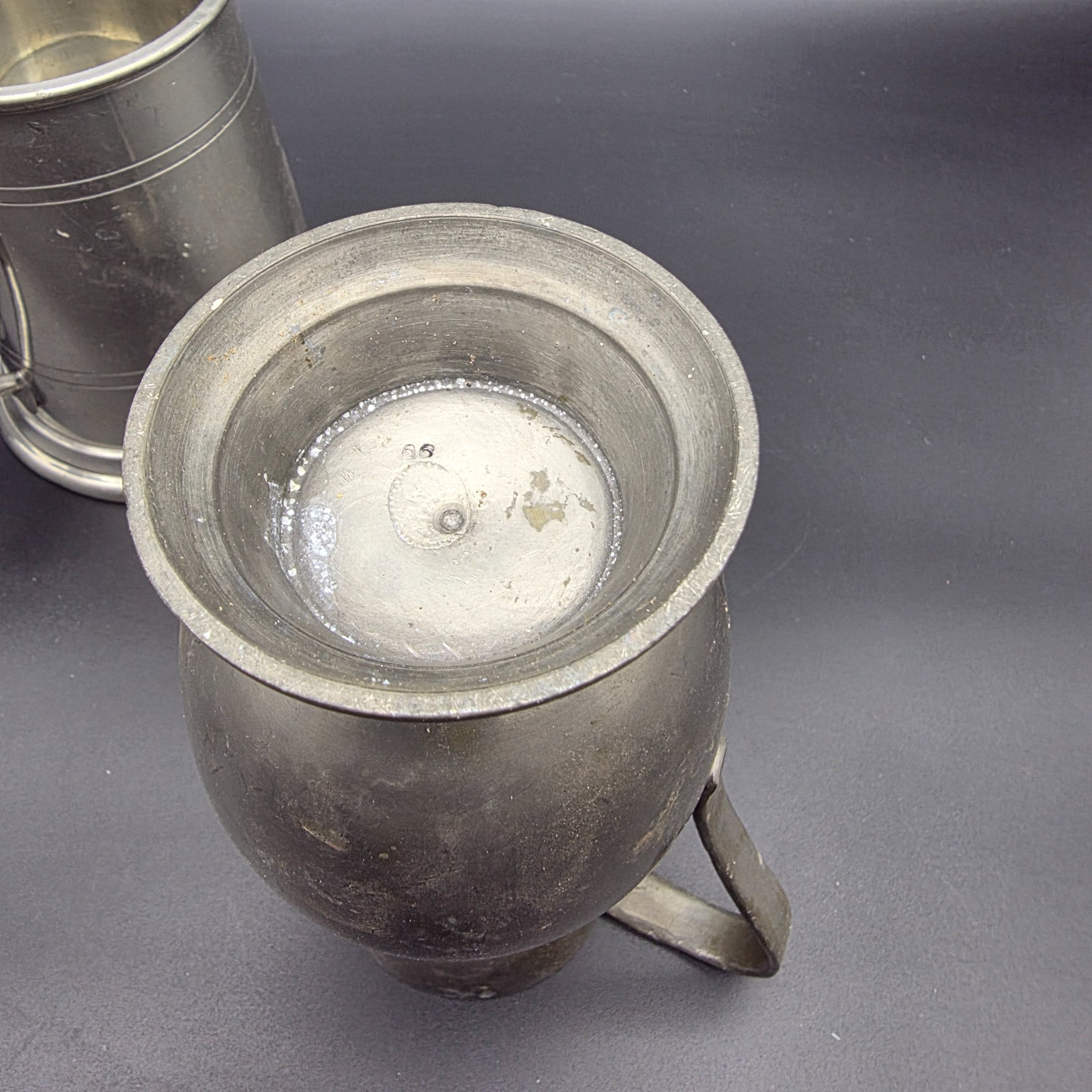 A collection of three traditional English pewter vessels, including a tankard with a unique nude figure handle, and two pitchers. These pieces originate from Sheffield, a city historically renowned for its metalwork and pewter manufacturing. - View 6
