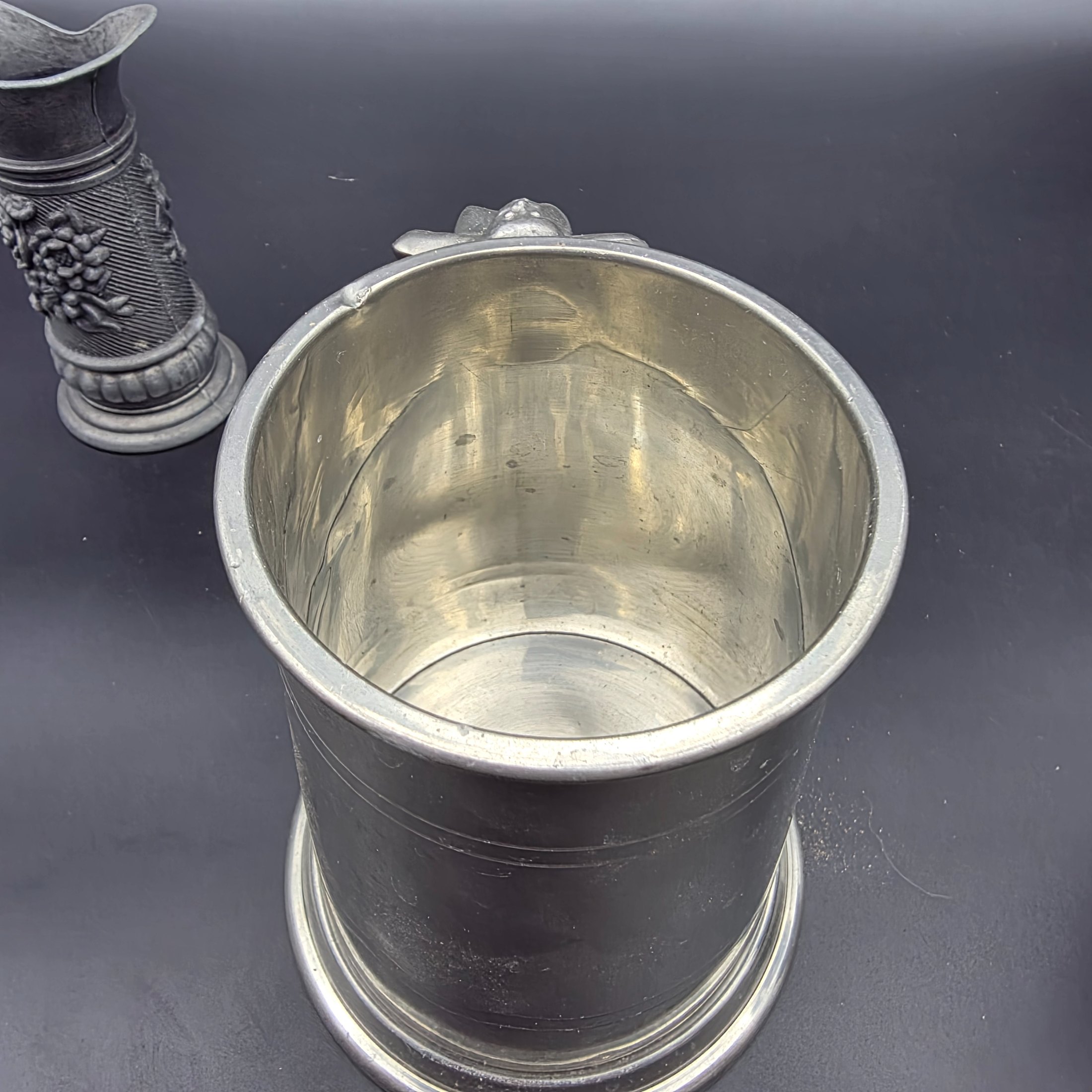A collection of three traditional English pewter vessels, including a tankard with a unique nude figure handle, and two pitchers. These pieces originate from Sheffield, a city historically renowned for its metalwork and pewter manufacturing. - View 7
