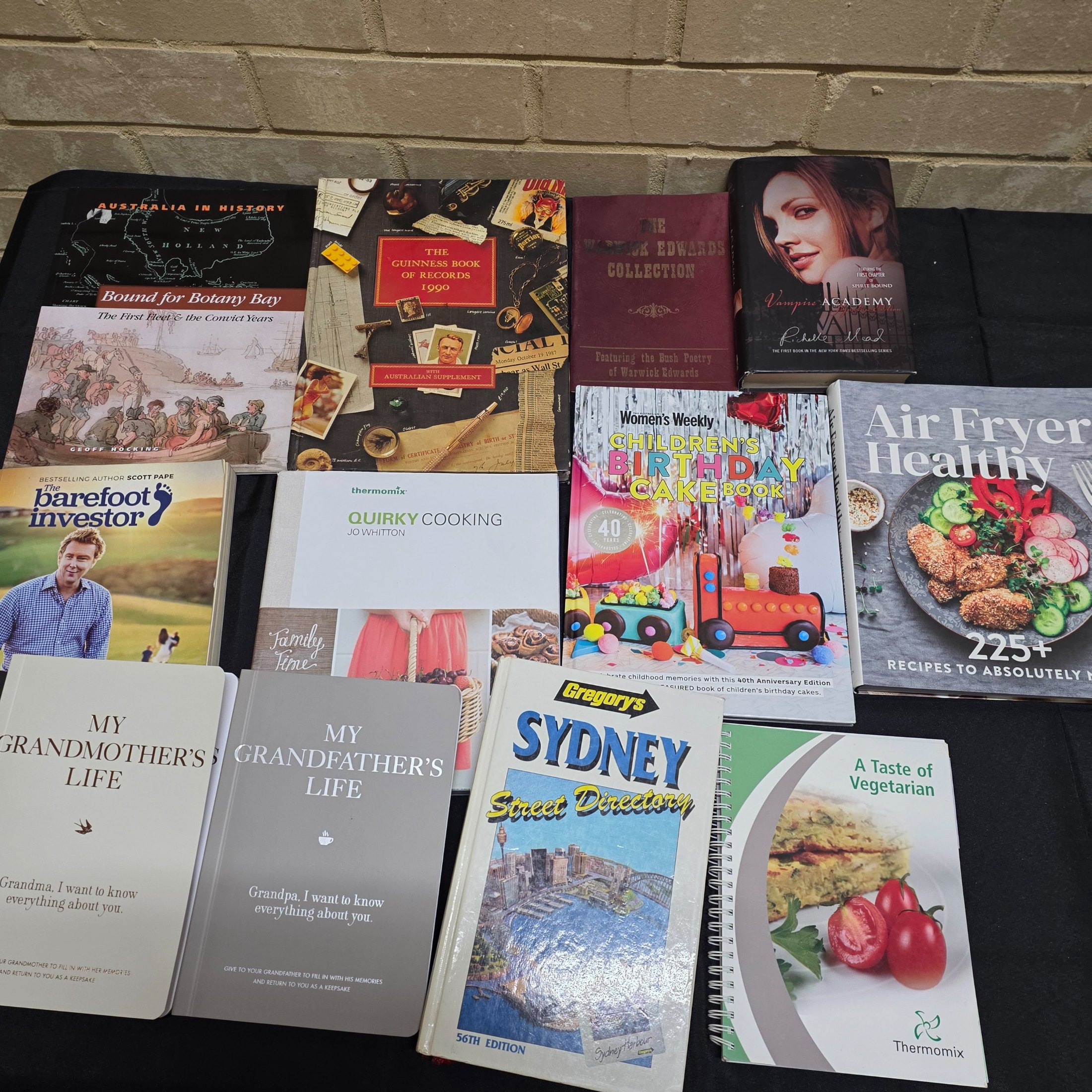 A diverse collection of thirteen pre-owned books, encompassing a range of genres from Australian history and finance to popular cookbooks and reference materials.