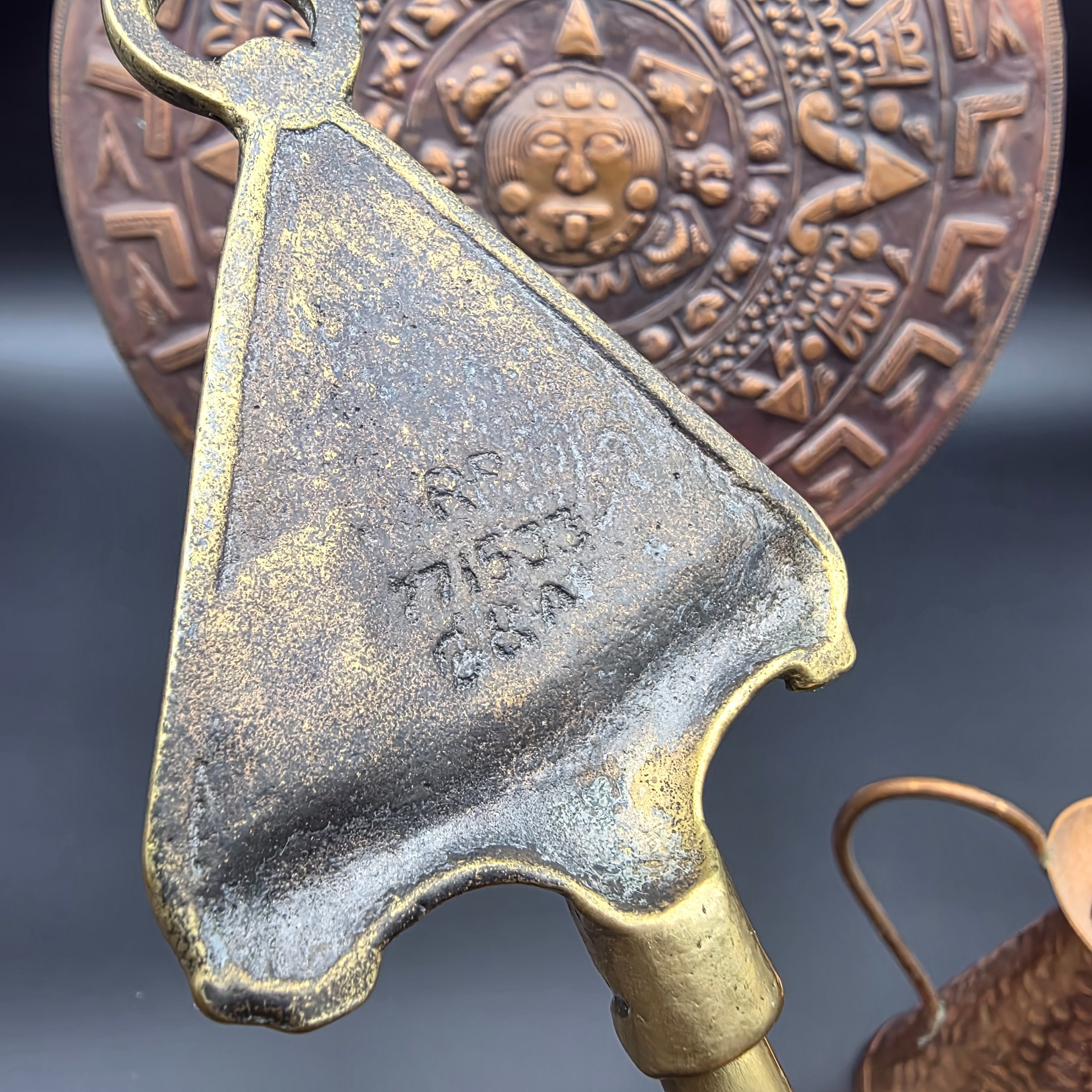 A collection of vintage copper and brass homewares, including an Aztec calendar wall hanging, pitchers, pots, and a Shakespeare-themed toasting fork. - View 5