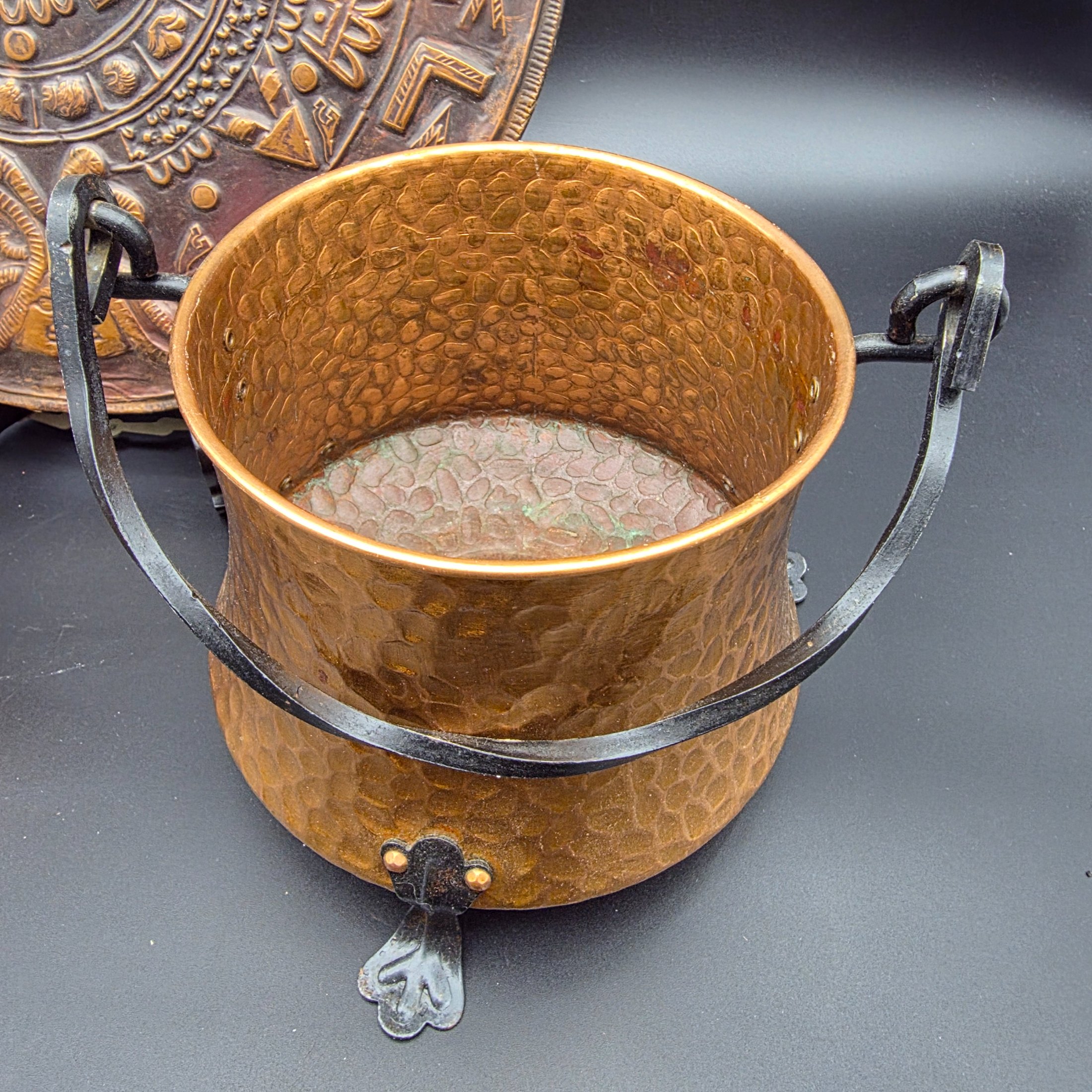 A collection of vintage copper and brass homewares, including an Aztec calendar wall hanging, pitchers, pots, and a Shakespeare-themed toasting fork. - View 8