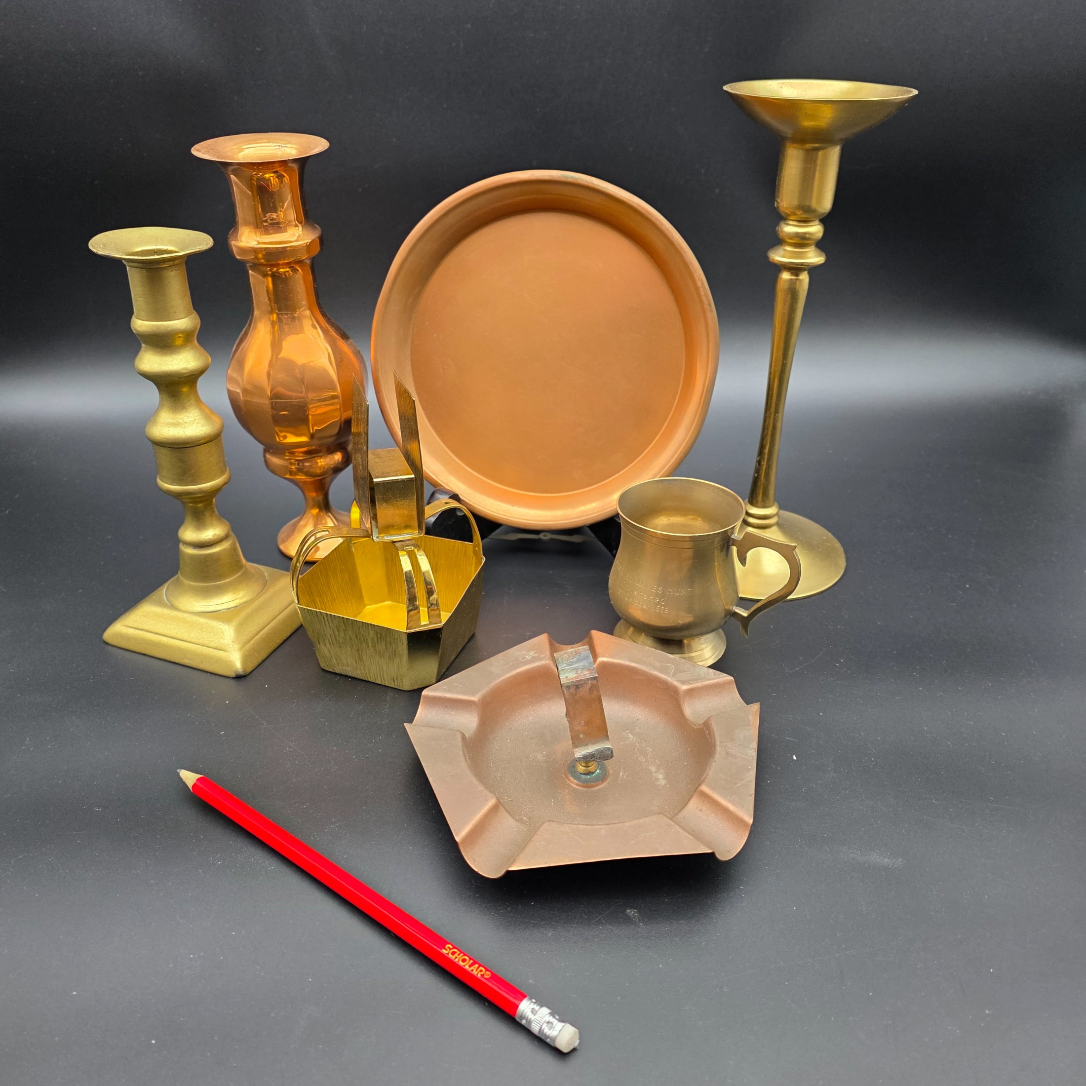 A collection of various vintage brass and copper sundries, including candlesticks, a decorative tray, a mug, an ashtray, and a small basket. - View 2