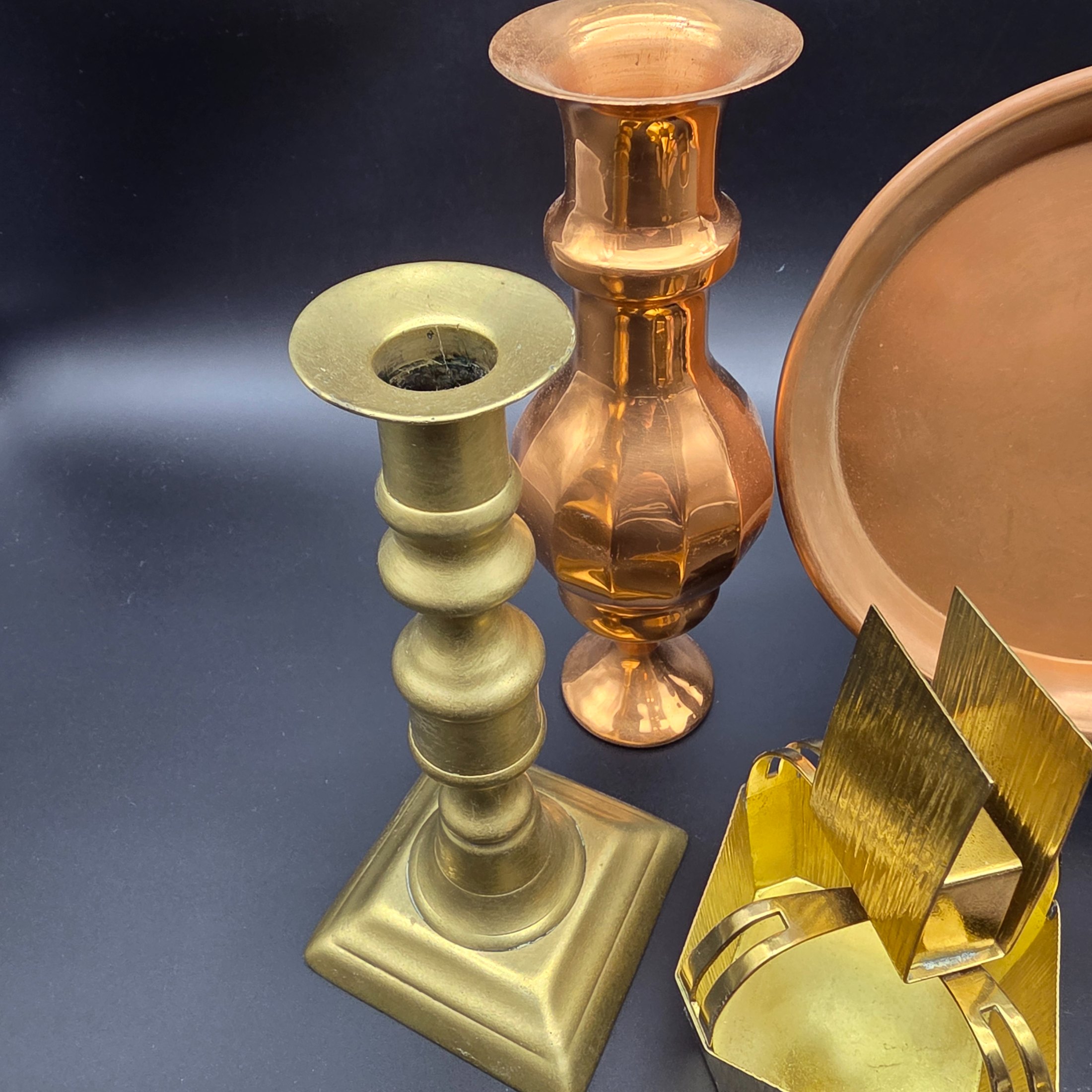 A collection of various vintage brass and copper sundries, including candlesticks, a decorative tray, a mug, an ashtray, and a small basket. - View 4