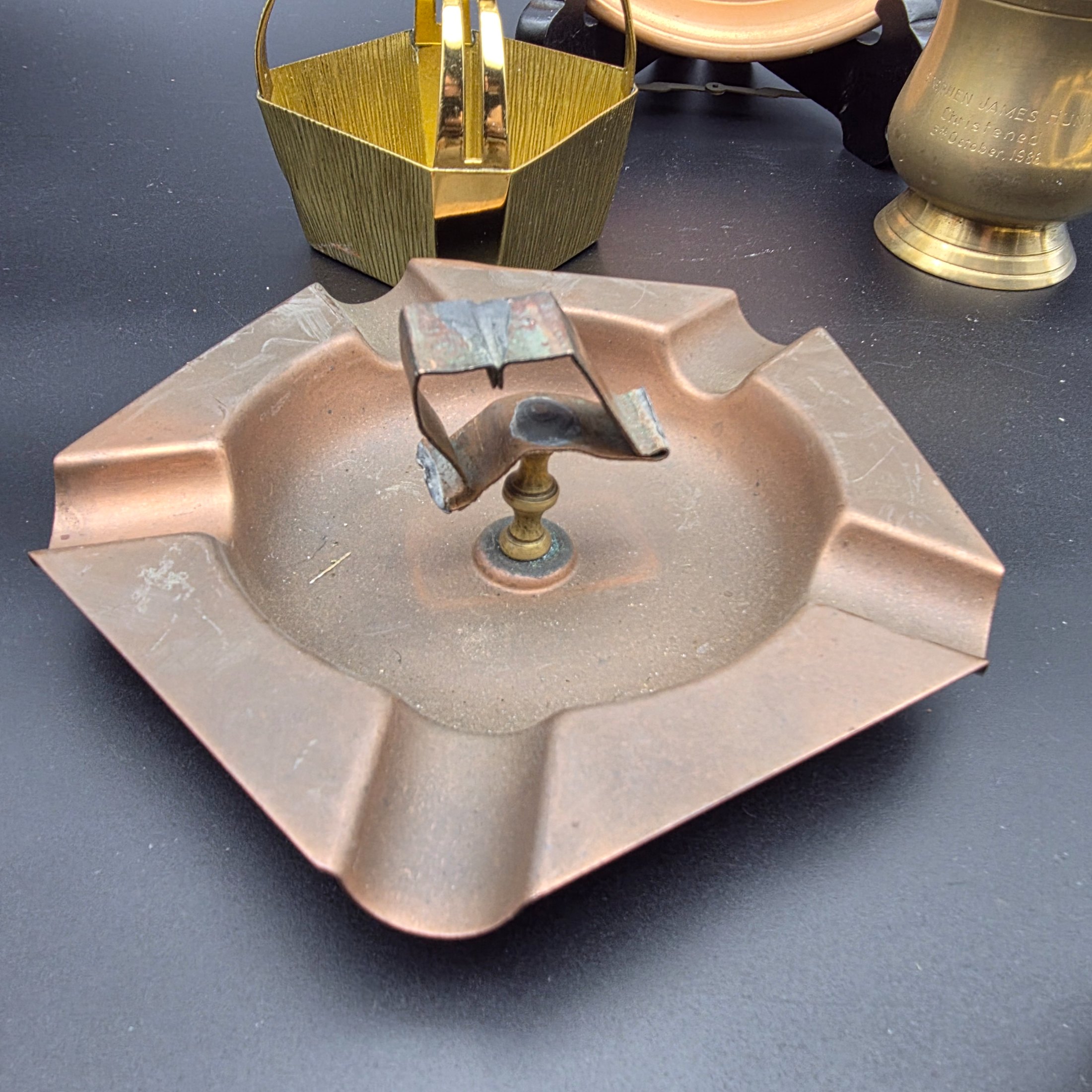 A collection of various vintage brass and copper sundries, including candlesticks, a decorative tray, a mug, an ashtray, and a small basket. - View 7