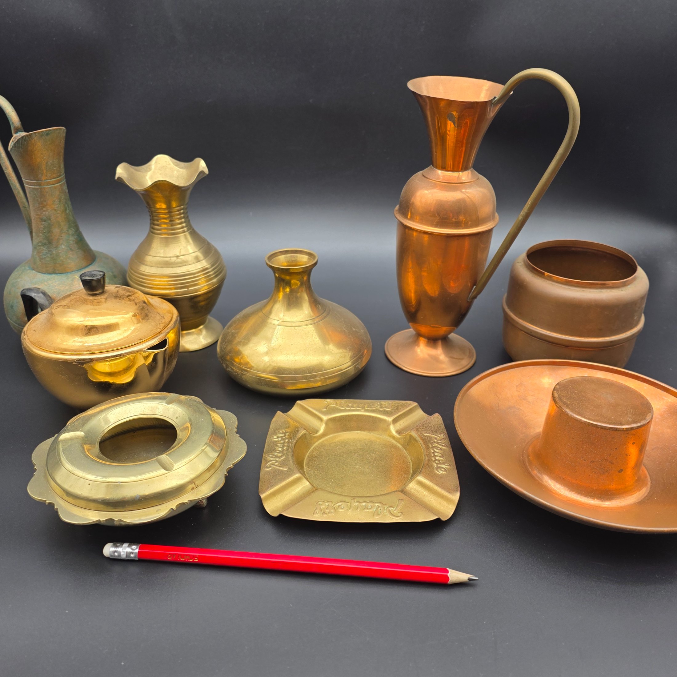 An appealing collection of eight assorted vintage brass and copper decorative items, including jugs, vases, pots, and ashtrays, showcasing varied forms and patinas from different eras and origins, ideal for display or use in period interiors. This lot includes an Australian-made Glama-Ware brass-finished stainless steel lidded pot and a 'Players' brand ashtray made in England. - View 2