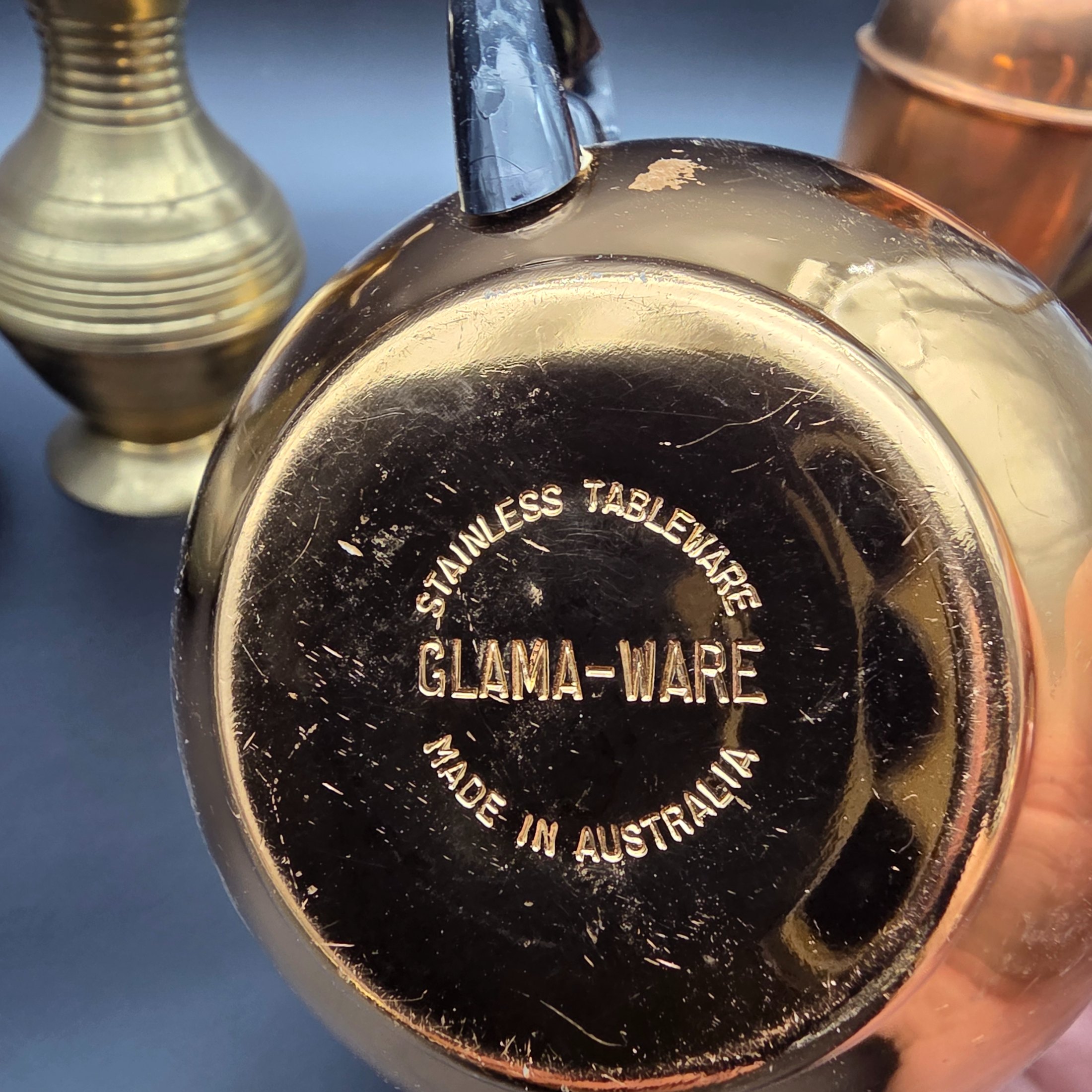 An appealing collection of eight assorted vintage brass and copper decorative items, including jugs, vases, pots, and ashtrays, showcasing varied forms and patinas from different eras and origins, ideal for display or use in period interiors. This lot includes an Australian-made Glama-Ware brass-finished stainless steel lidded pot and a 'Players' brand ashtray made in England. - View 6
