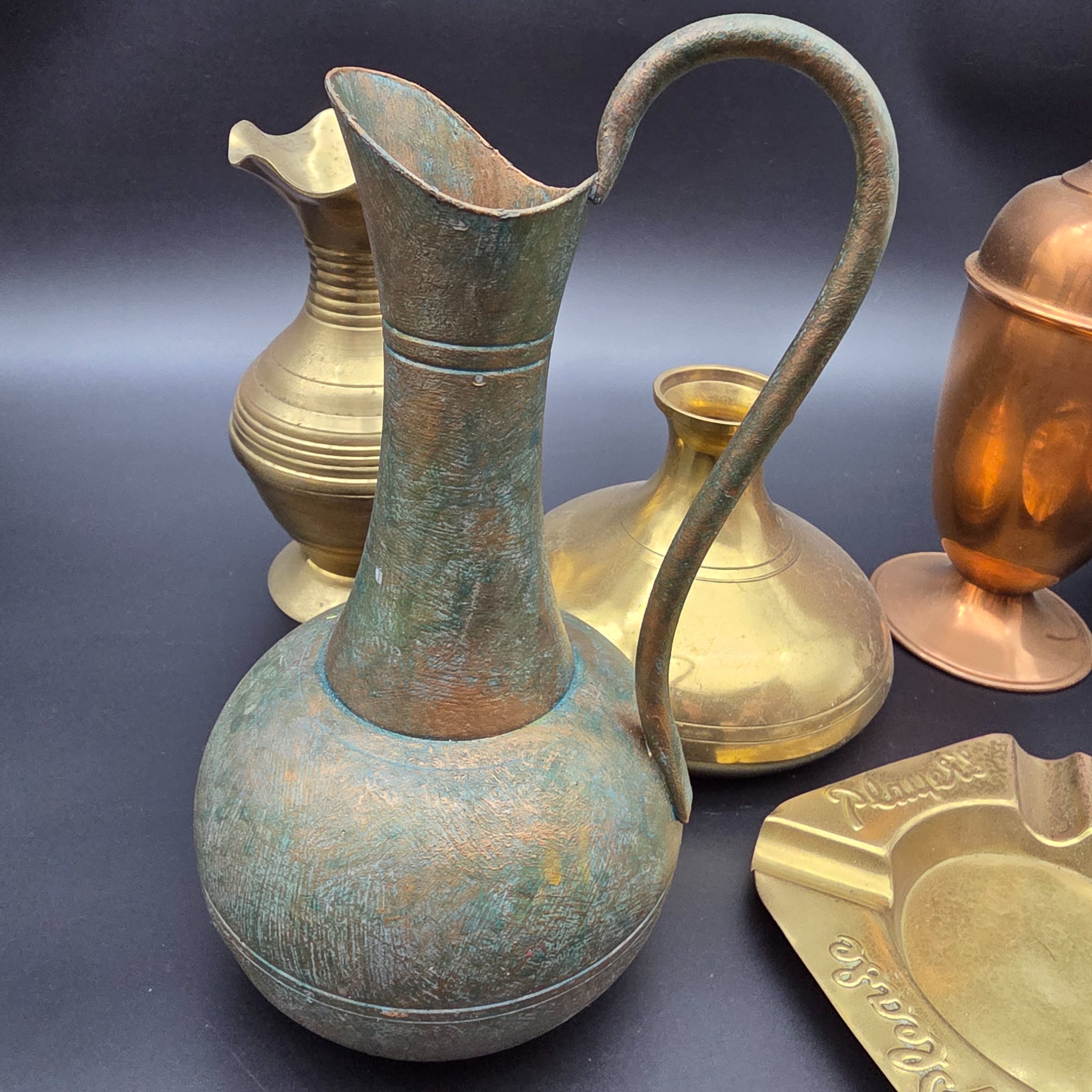 An appealing collection of eight assorted vintage brass and copper decorative items, including jugs, vases, pots, and ashtrays, showcasing varied forms and patinas from different eras and origins, ideal for display or use in period interiors. This lot includes an Australian-made Glama-Ware brass-finished stainless steel lidded pot and a 'Players' brand ashtray made in England. - View 8