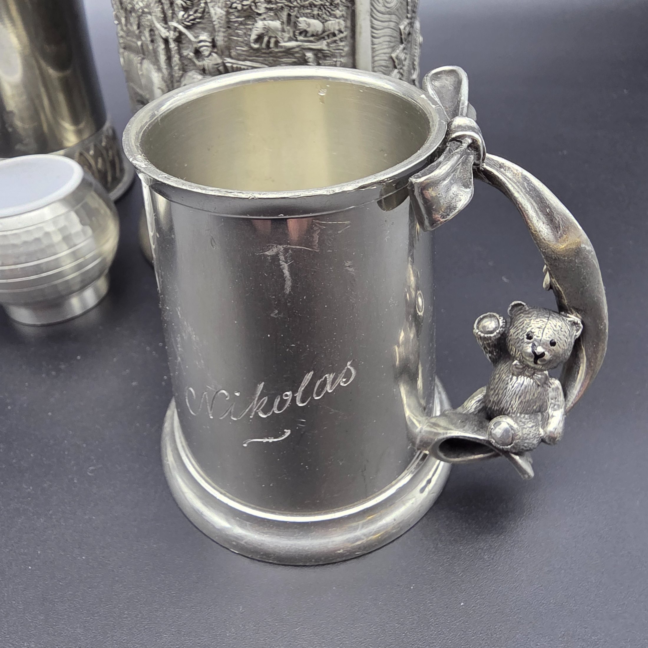 A collection of vintage pewter items including decorative mugs, cups, and small vases, displaying various finishes and makers' marks. - View 2