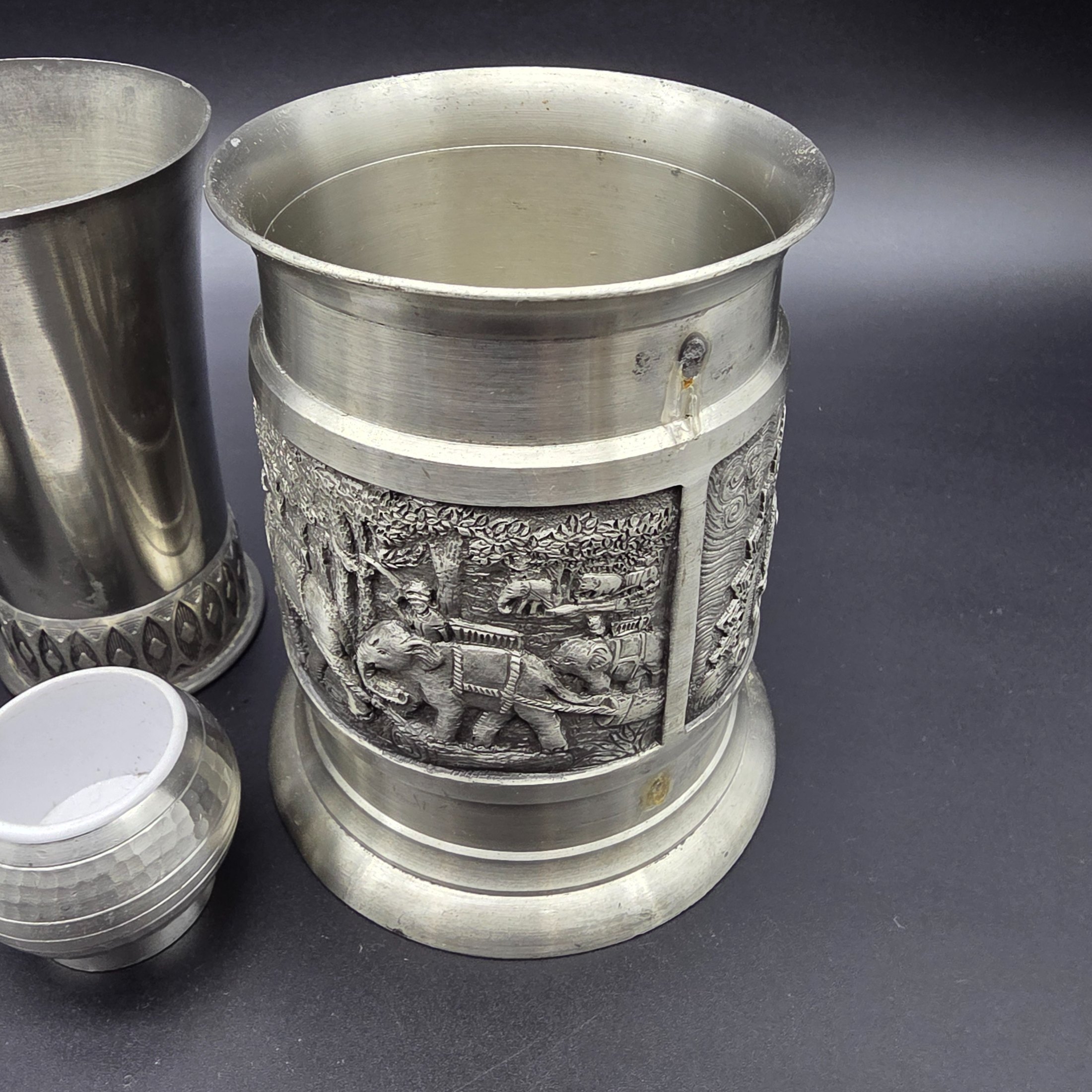 A collection of vintage pewter items including decorative mugs, cups, and small vases, displaying various finishes and makers' marks. - View 4
