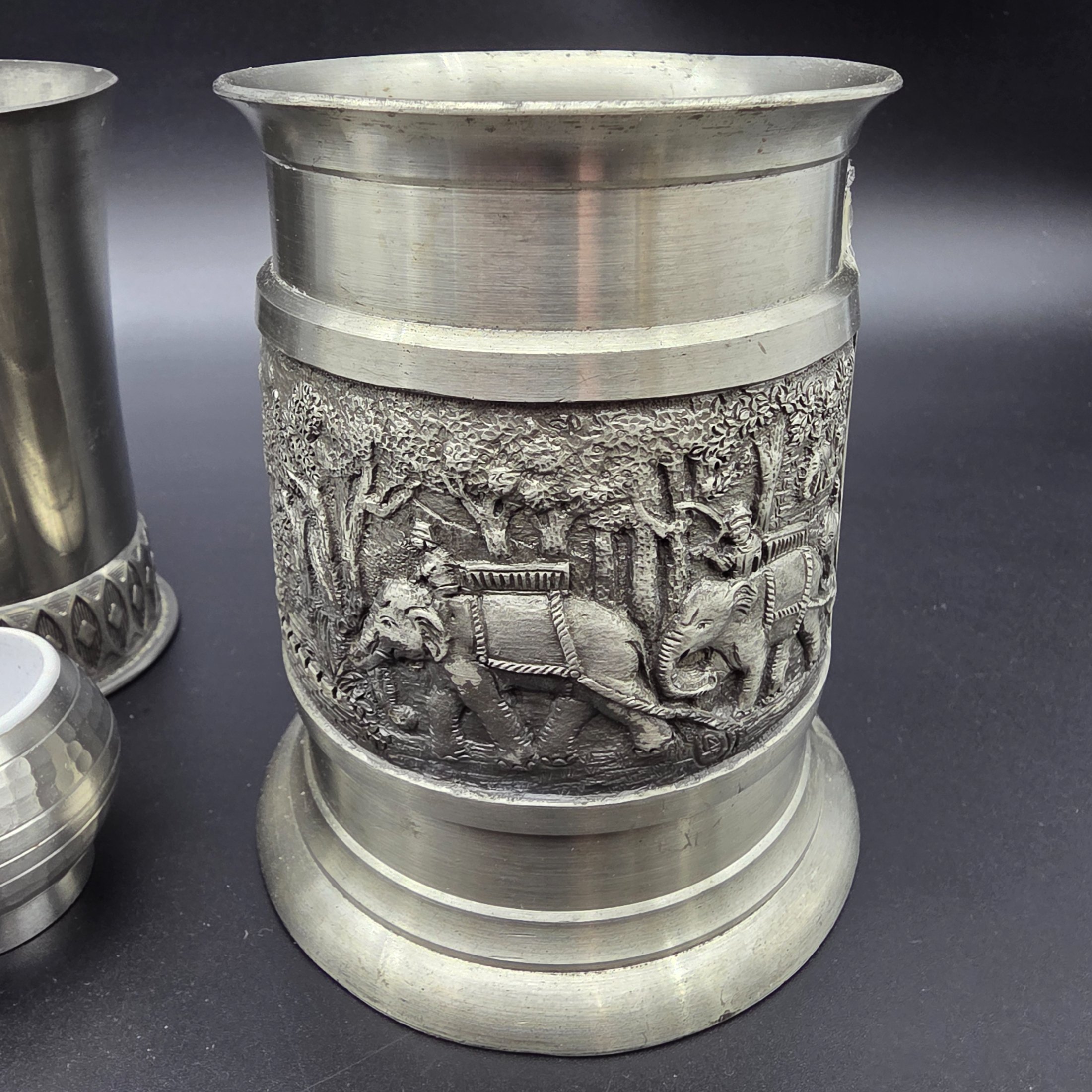 A collection of vintage pewter items including decorative mugs, cups, and small vases, displaying various finishes and makers' marks. - View 5