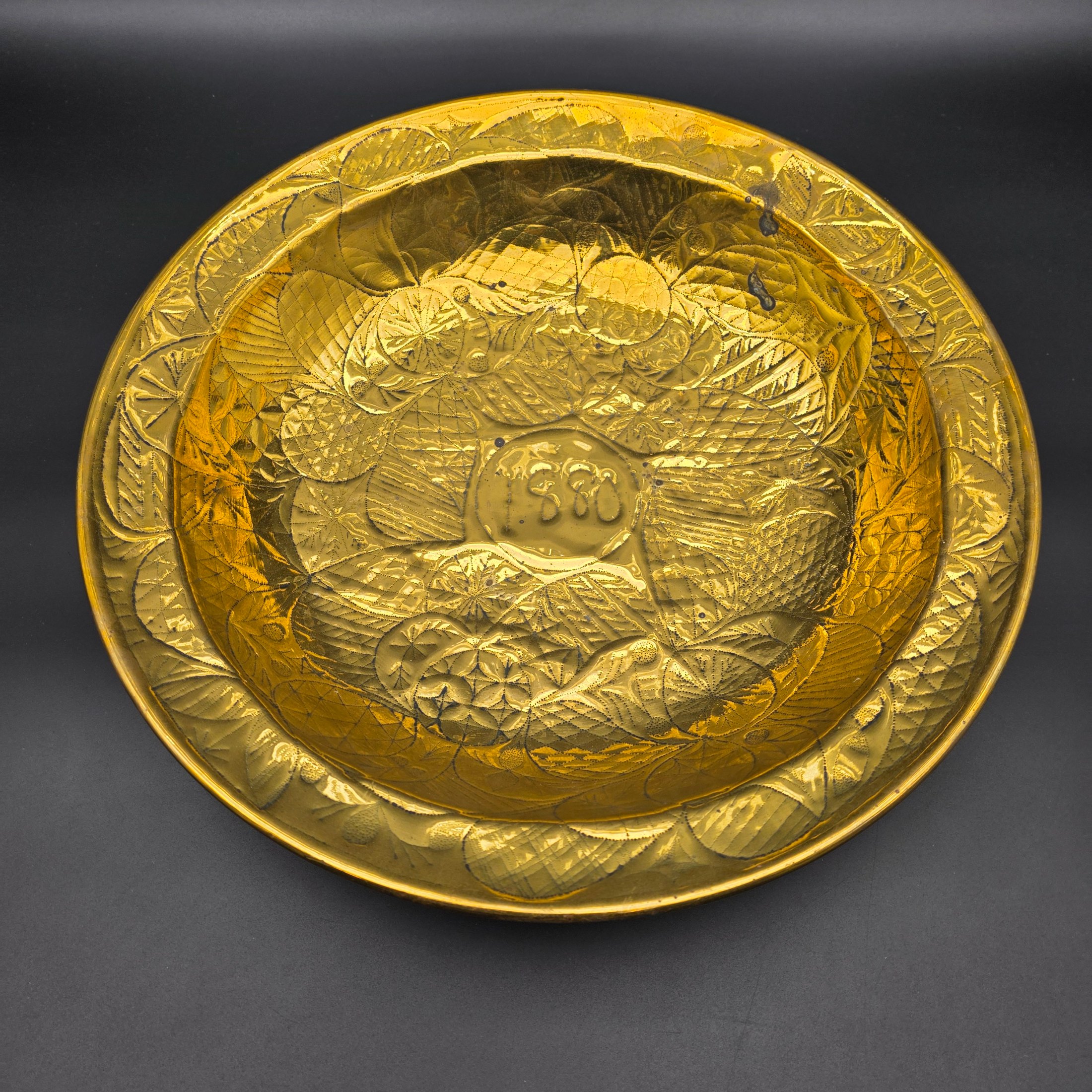 A substantial Victorian decorative basin, meticulously crafted from embossed brass and dated 1880. This piece showcases intricate repoussé and chased patterns, characteristic of the era's decorative metalwork, and would have served as an opulent display item or lavabo basin.