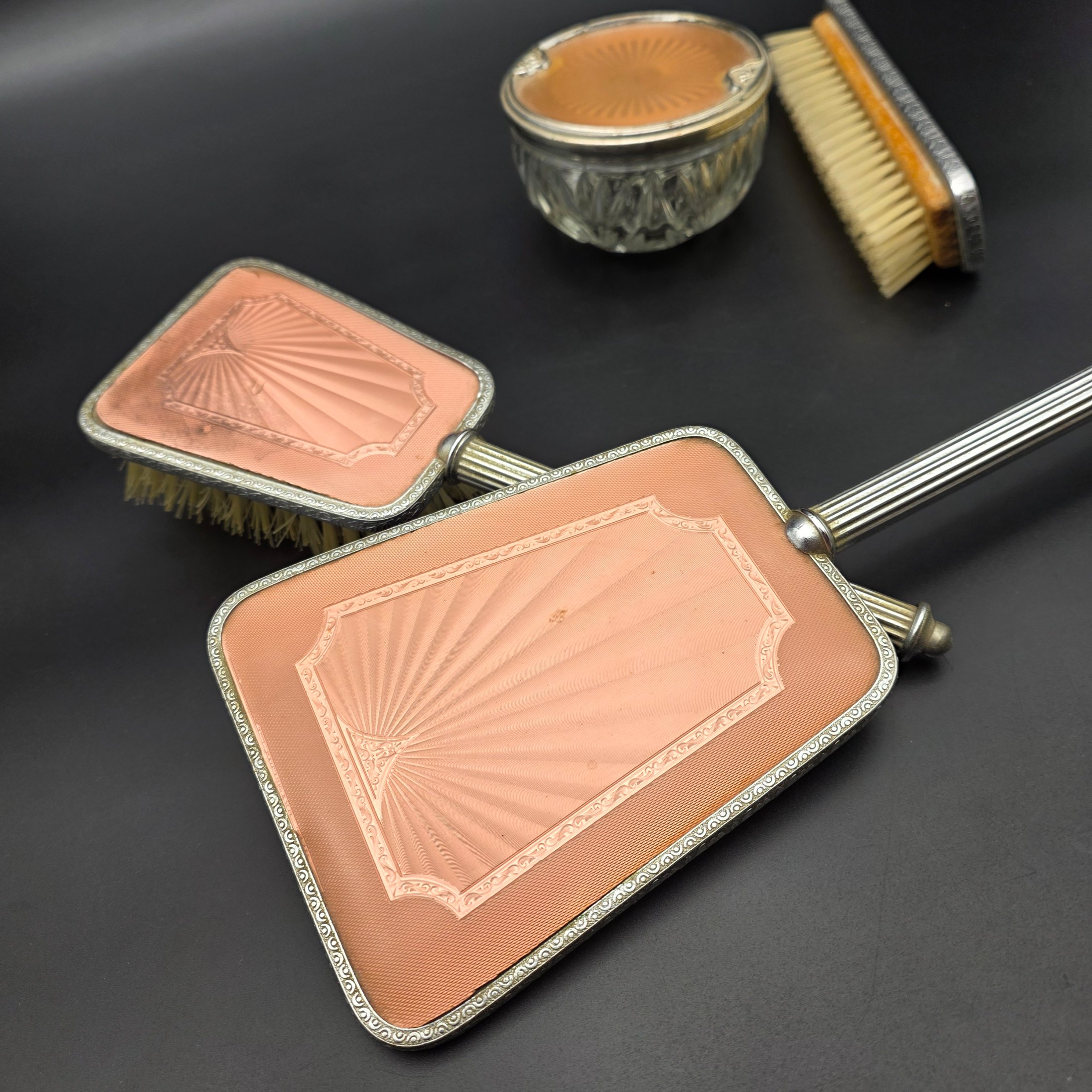A five-piece vintage Art Deco dressing table vanity set, featuring a hand mirror, two brushes, and a lidded glass powder jar, all with silver-tone metal and rose-gold toned celluloid fan-patterned inserts. - View 6
