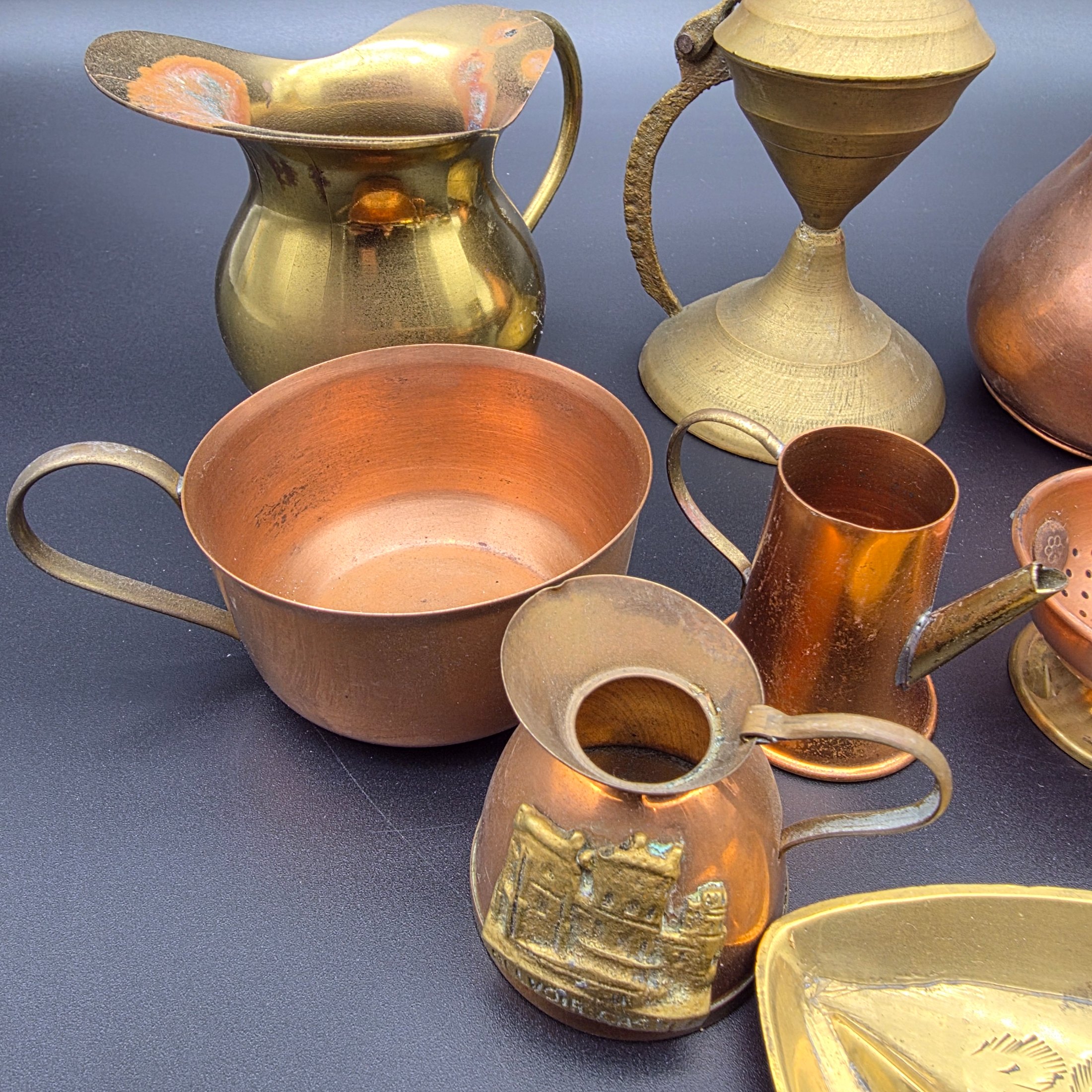 A diverse collection of antique and vintage decorative items, primarily crafted from brass and copper, showcasing various forms such as jugs, a censer, a figurine, and an ornate leaf-shaped dish. - View 3