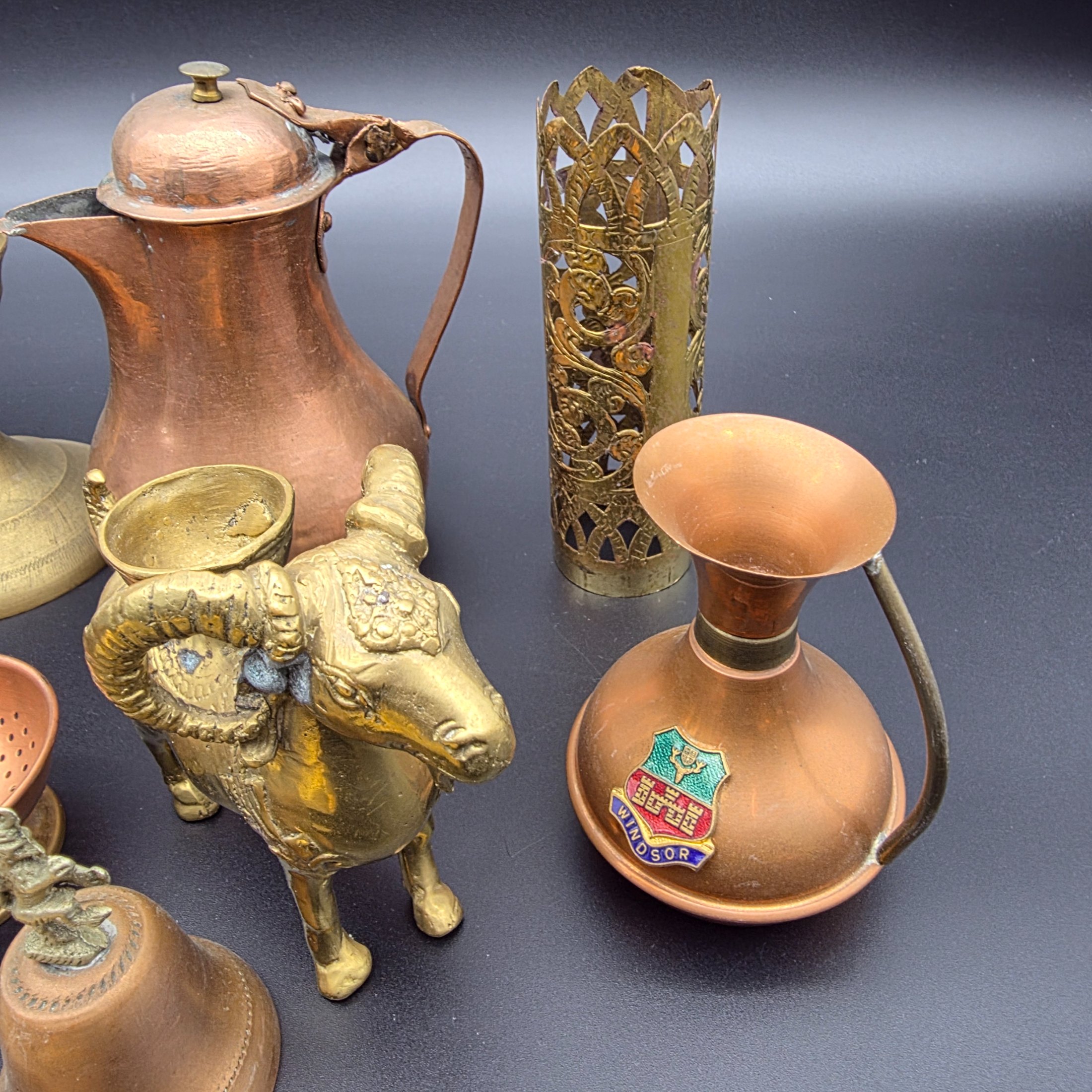 A diverse collection of antique and vintage decorative items, primarily crafted from brass and copper, showcasing various forms such as jugs, a censer, a figurine, and an ornate leaf-shaped dish. - View 5