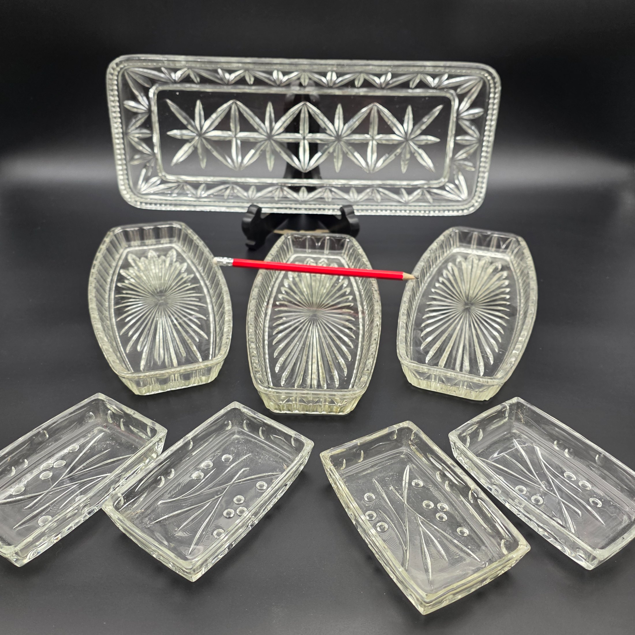 A decorative vintage clear pressed glass serving set, featuring one large rectangular tray, three oval dishes, and four smaller rectangular dishes, showcasing intricate pressed patterns. - View 2