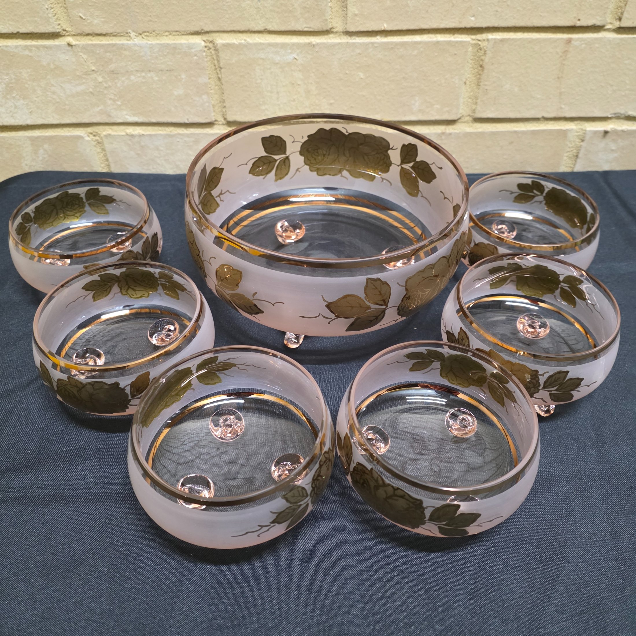 A charming vintage frosted pink and gold glass dessert set, comprising one large serving bowl and six smaller individual bowls, likely dating from the mid-20th century.