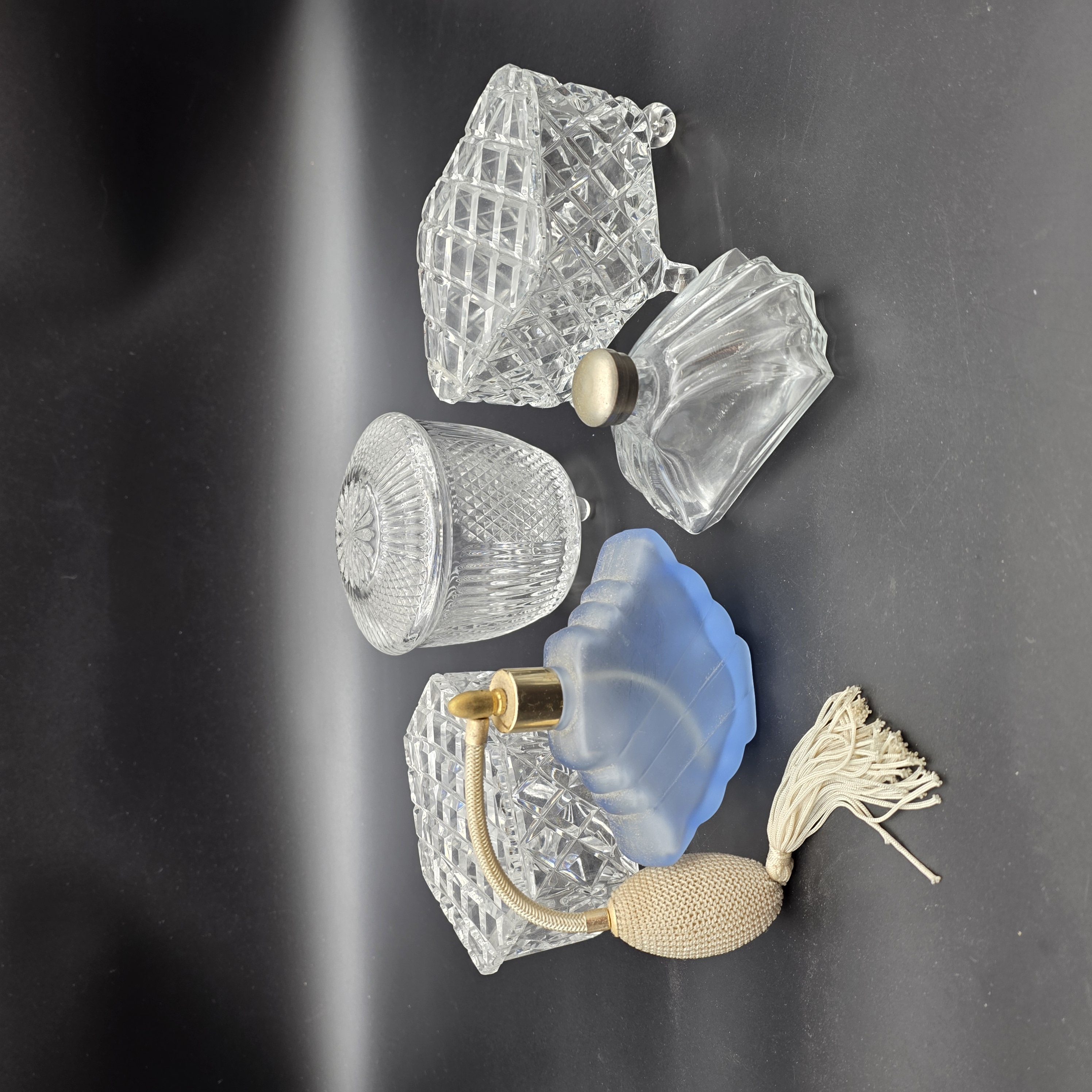 A charming collection of vintage cut glass and frosted vanity accessories, including lidded boxes, perfume bottles, and an atomizer, likely from the mid-20th century.