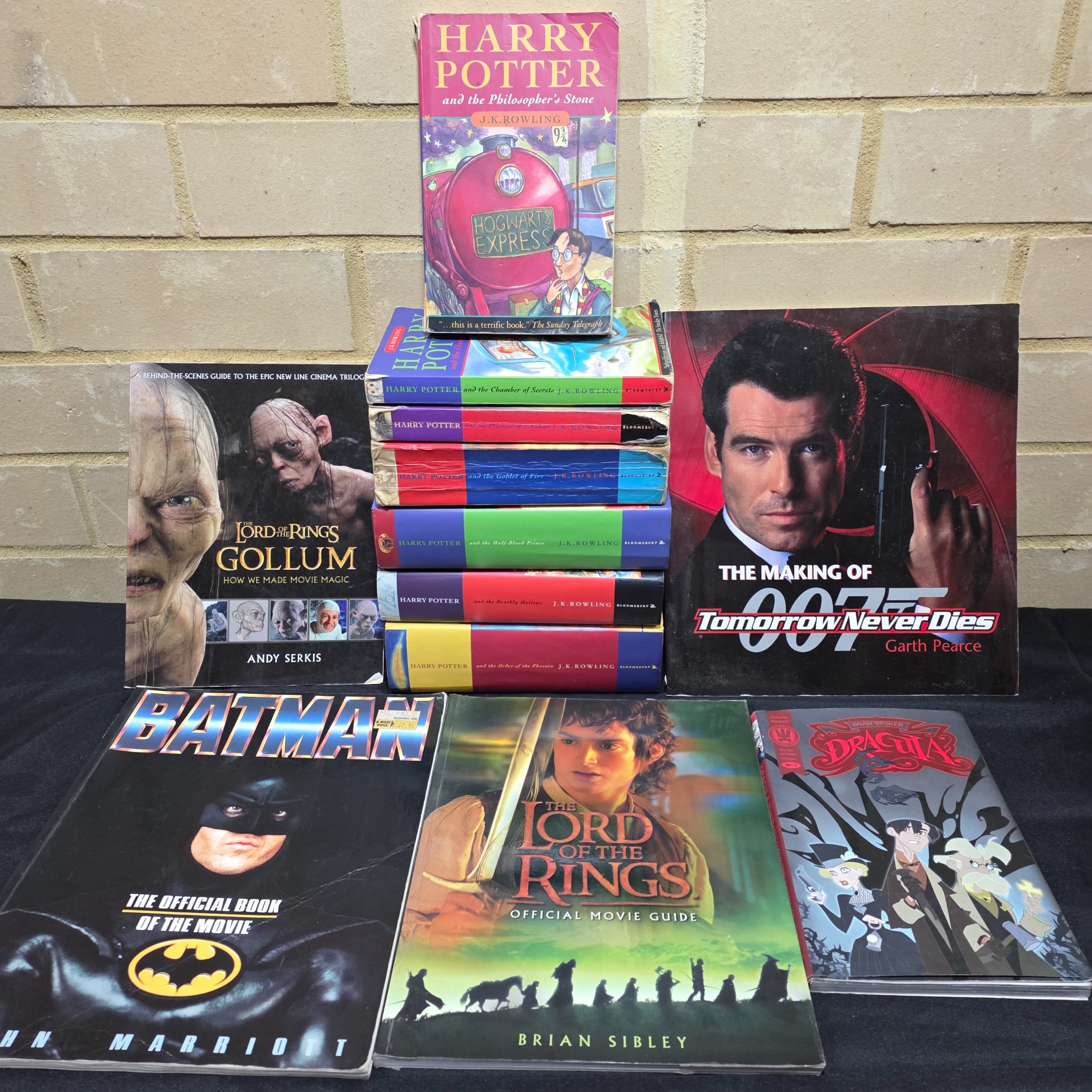 A collection of popular culture books, including a complete set of seven Harry Potter novels and various movie companion books like 'The Making of 007 Tomorrow Never Dies' and 'The Lord of the Rings Gollum'.