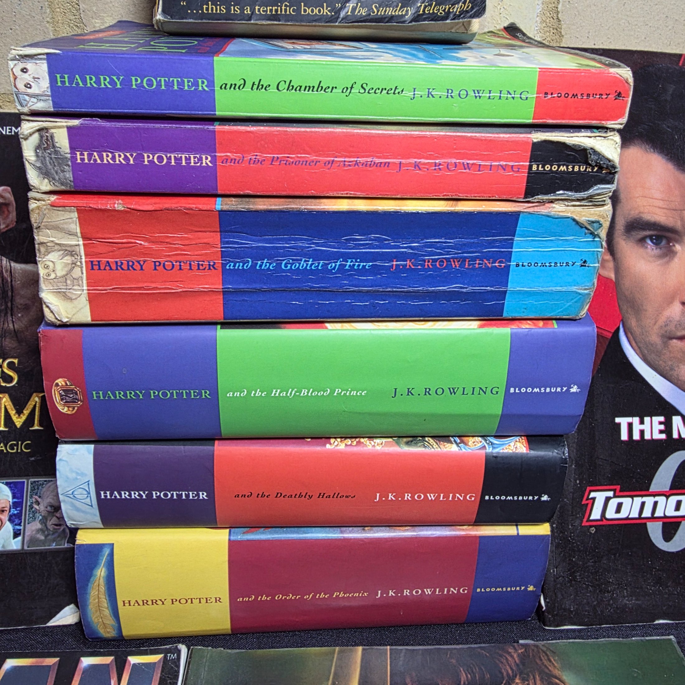 A collection of popular culture books, including a complete set of seven Harry Potter novels and various movie companion books like 'The Making of 007 Tomorrow Never Dies' and 'The Lord of the Rings Gollum'. - View 2