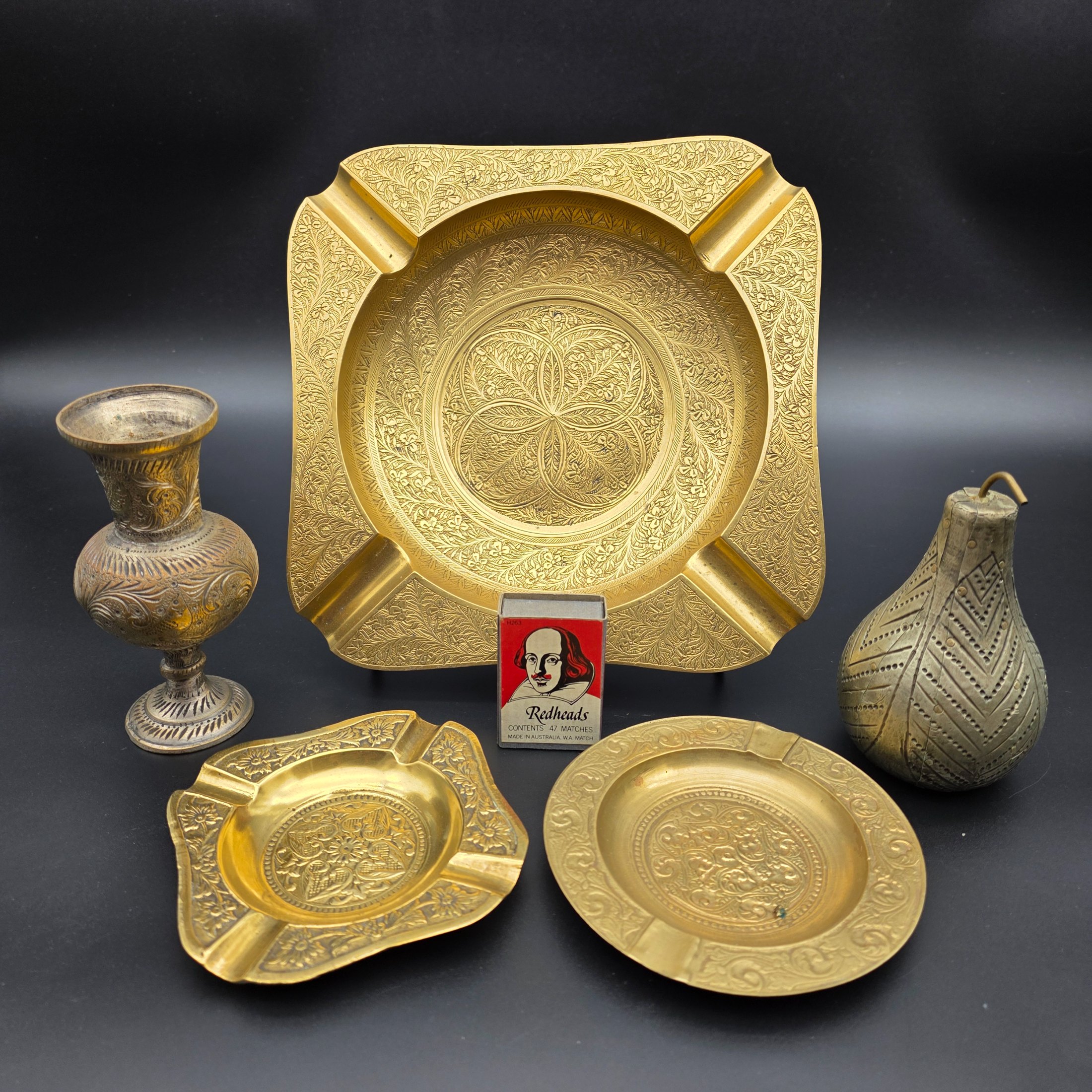 A collection of five vintage engraved brass and bronze decorative items, including three ashtrays, a vase, and a pear-shaped container. - View 2