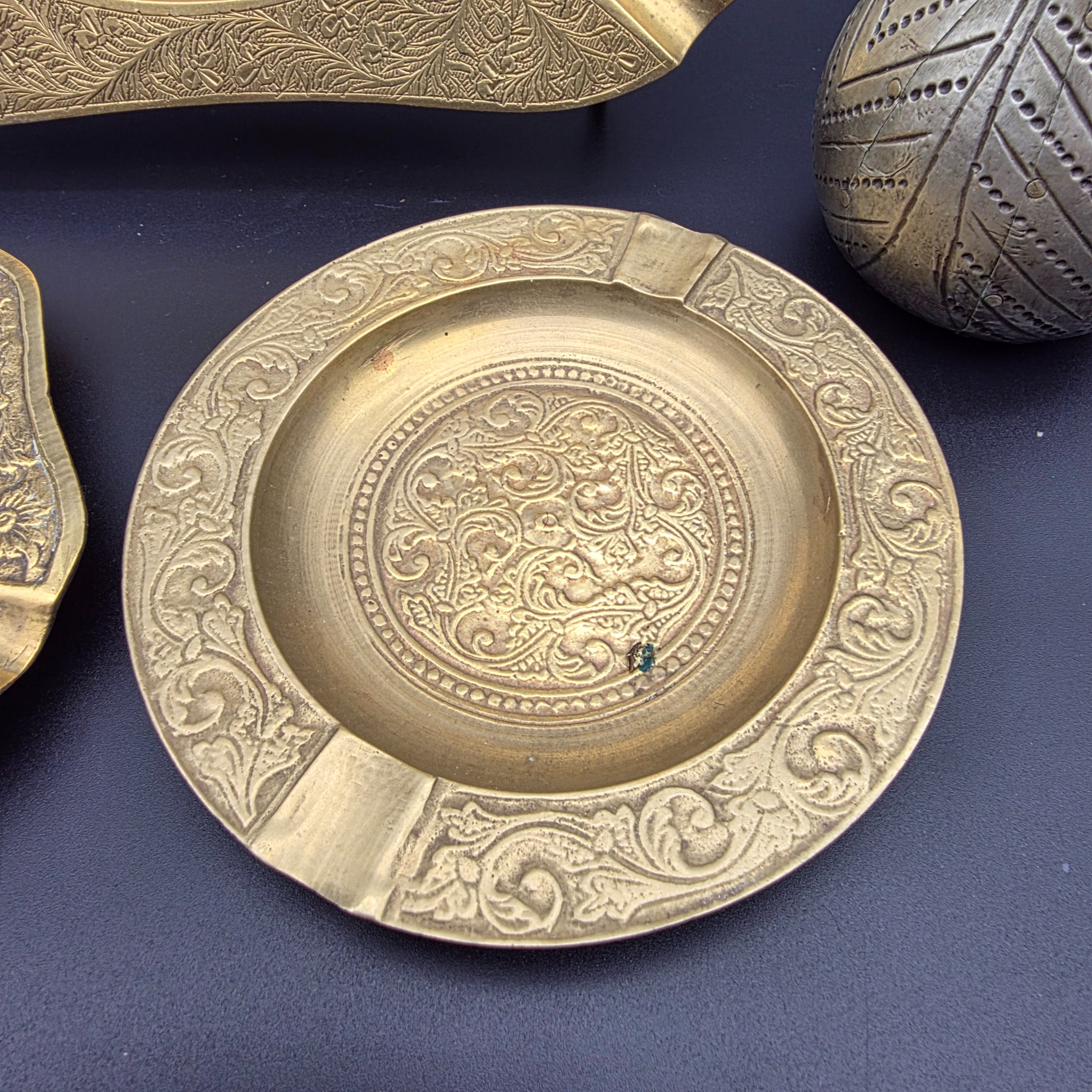 A collection of five vintage engraved brass and bronze decorative items, including three ashtrays, a vase, and a pear-shaped container. - View 3